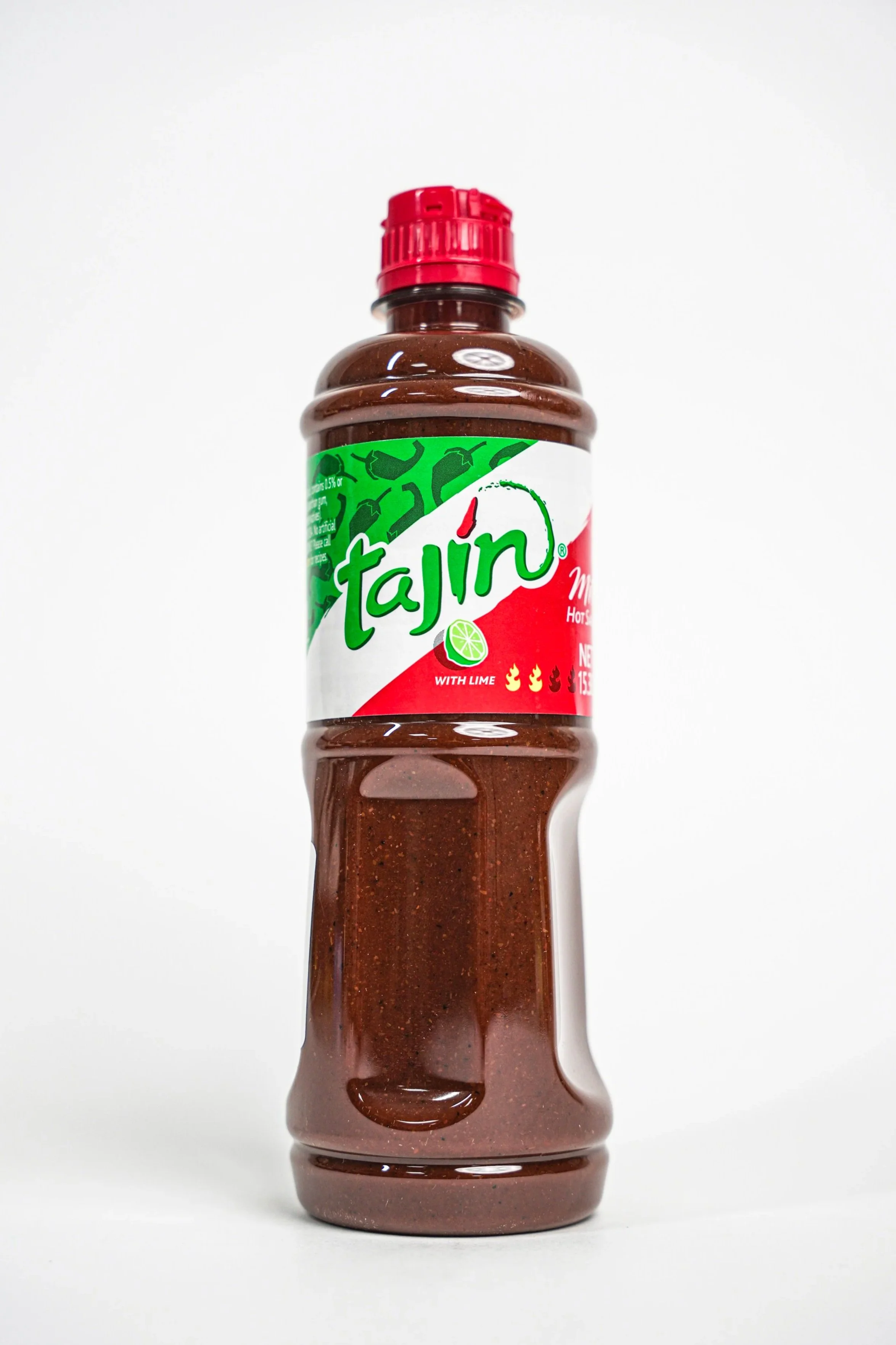 A bottle of Tajin hot sauce with lime flavor, featuring a red cap and a label with green, white, and red colors, positioned upright on a white background.