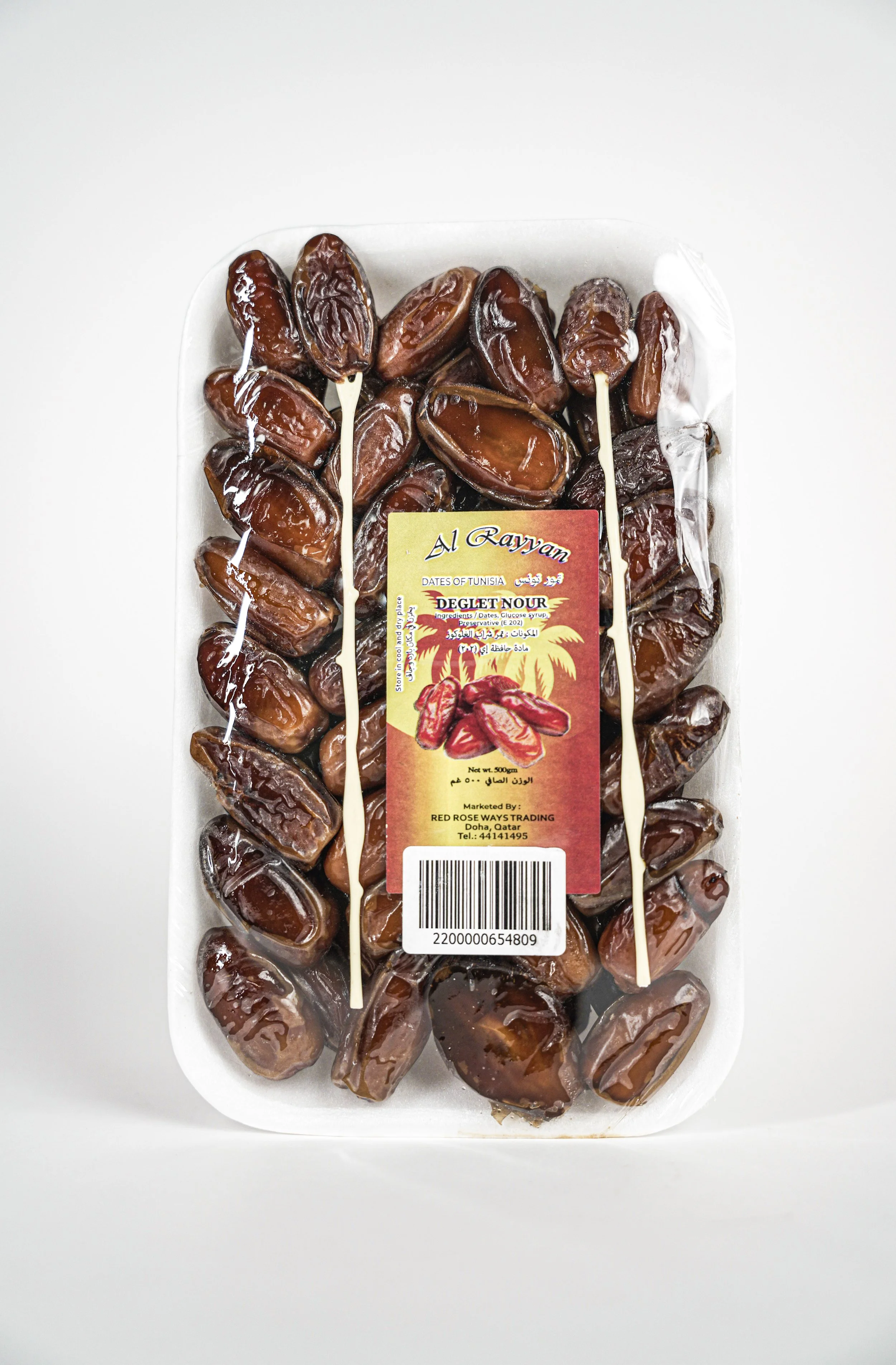 Packaged Medjool dates with a colorful label showing date illustrations, from Tunisia, marked by Red Rose Ways Trading, with barcode