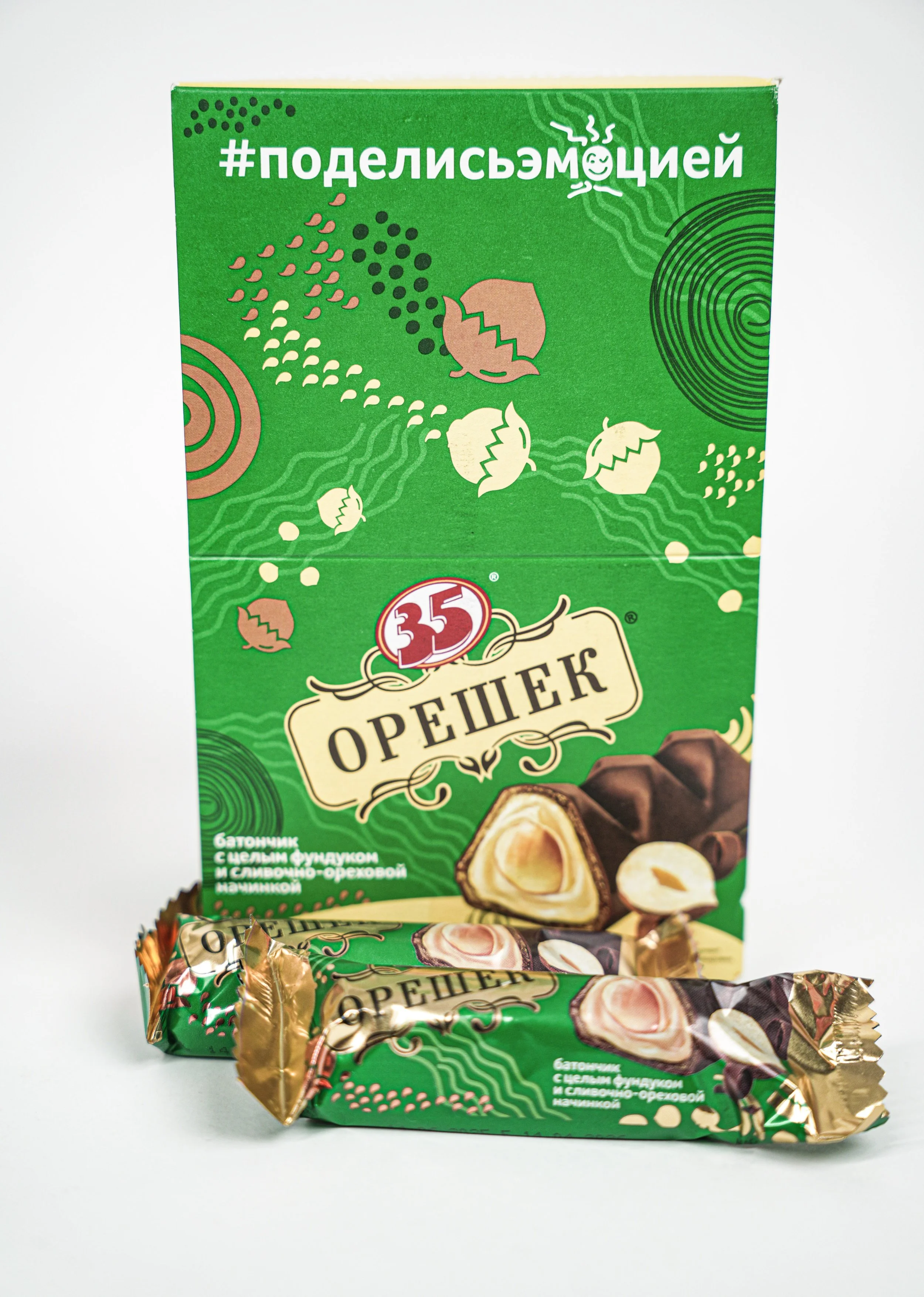 Russian candy with nuts and caramel flavor, featuring green packaging and two wrapped candies in front.
