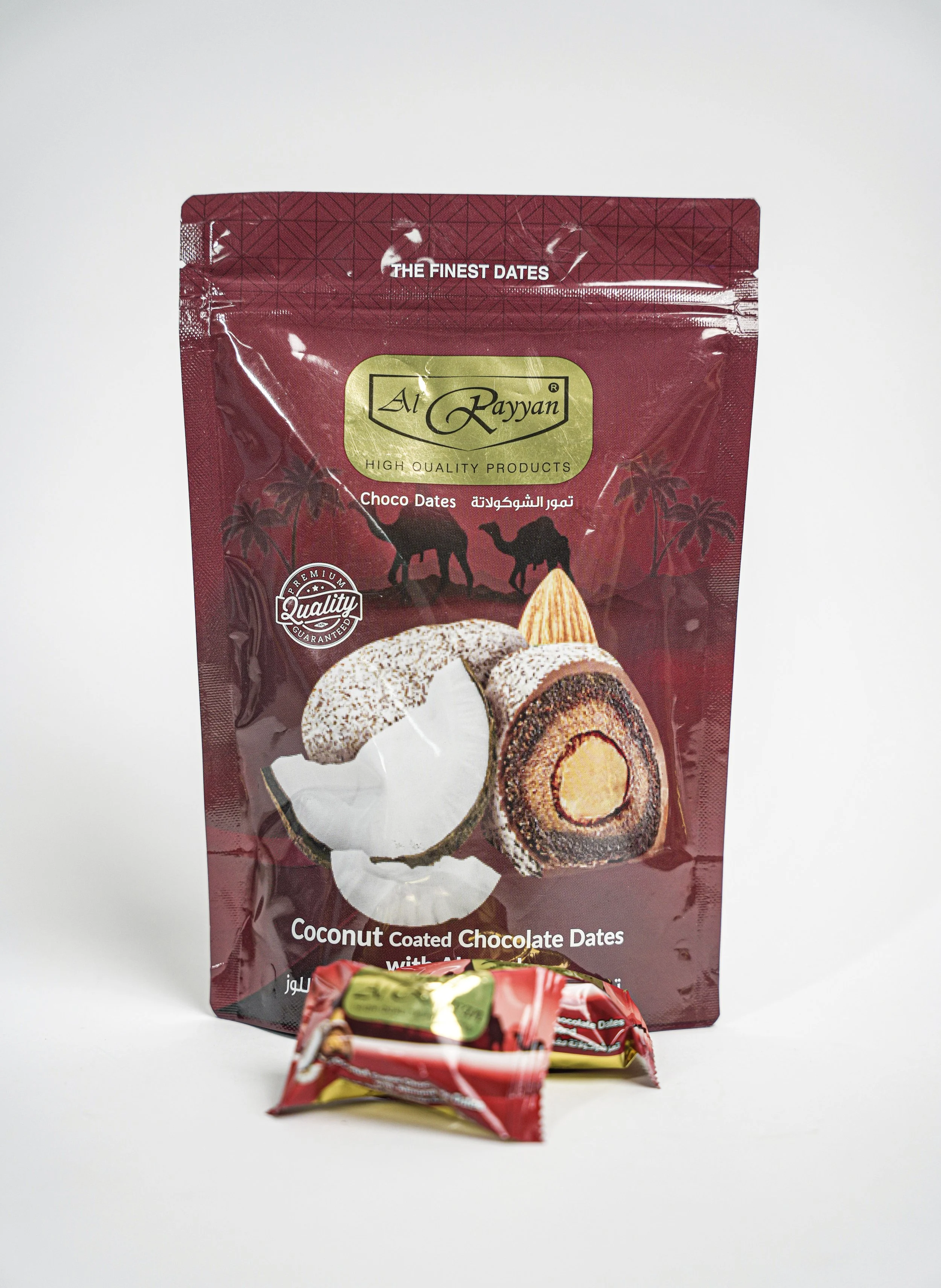 A package of Al Rayyan coconut coated chocolate dates with two smaller wrapped date candies in front, set against a plain white background.