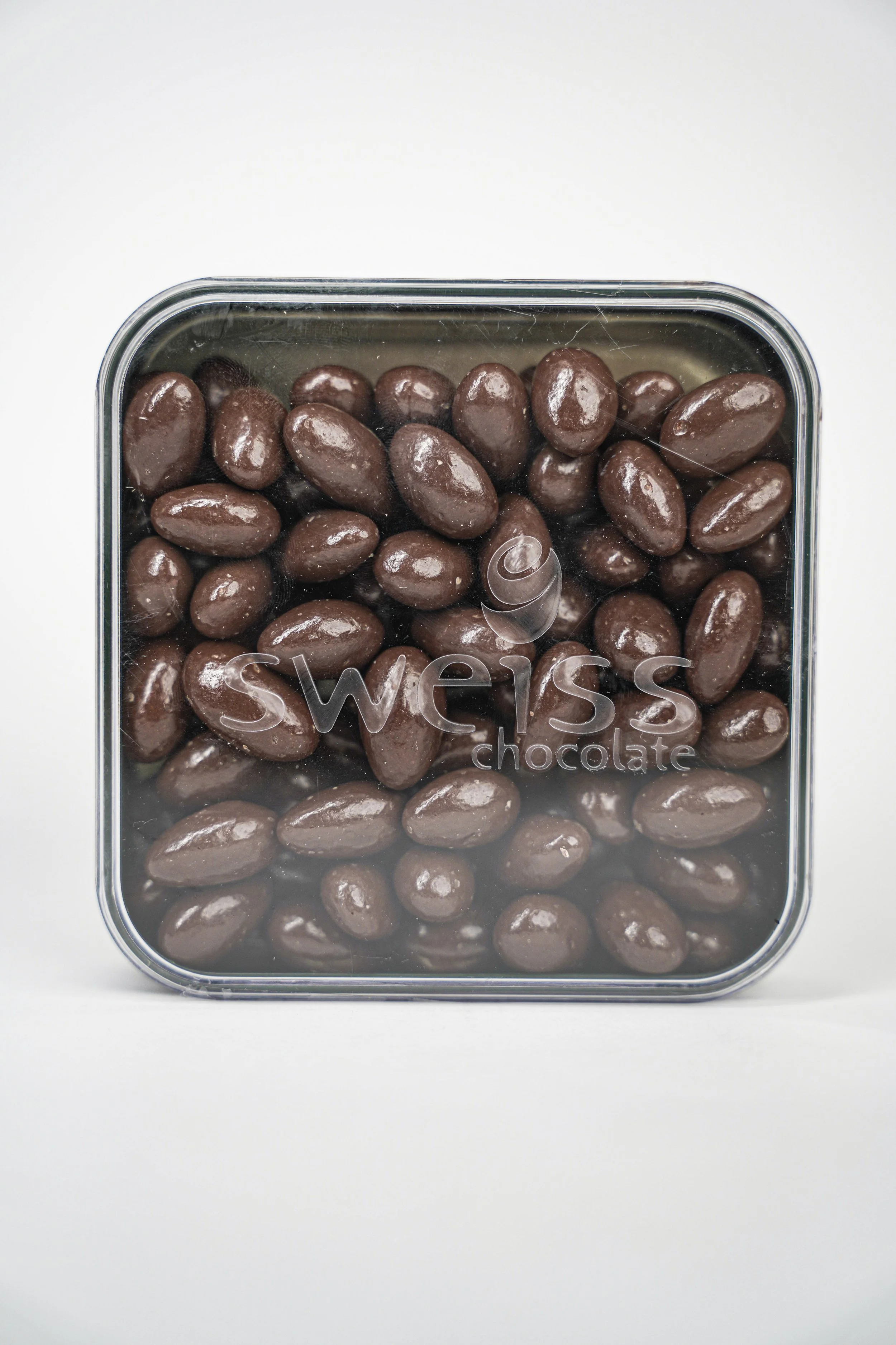 A clear plastic container filled with chocolate-covered almonds, with the brand name 'Swess' on the lid.