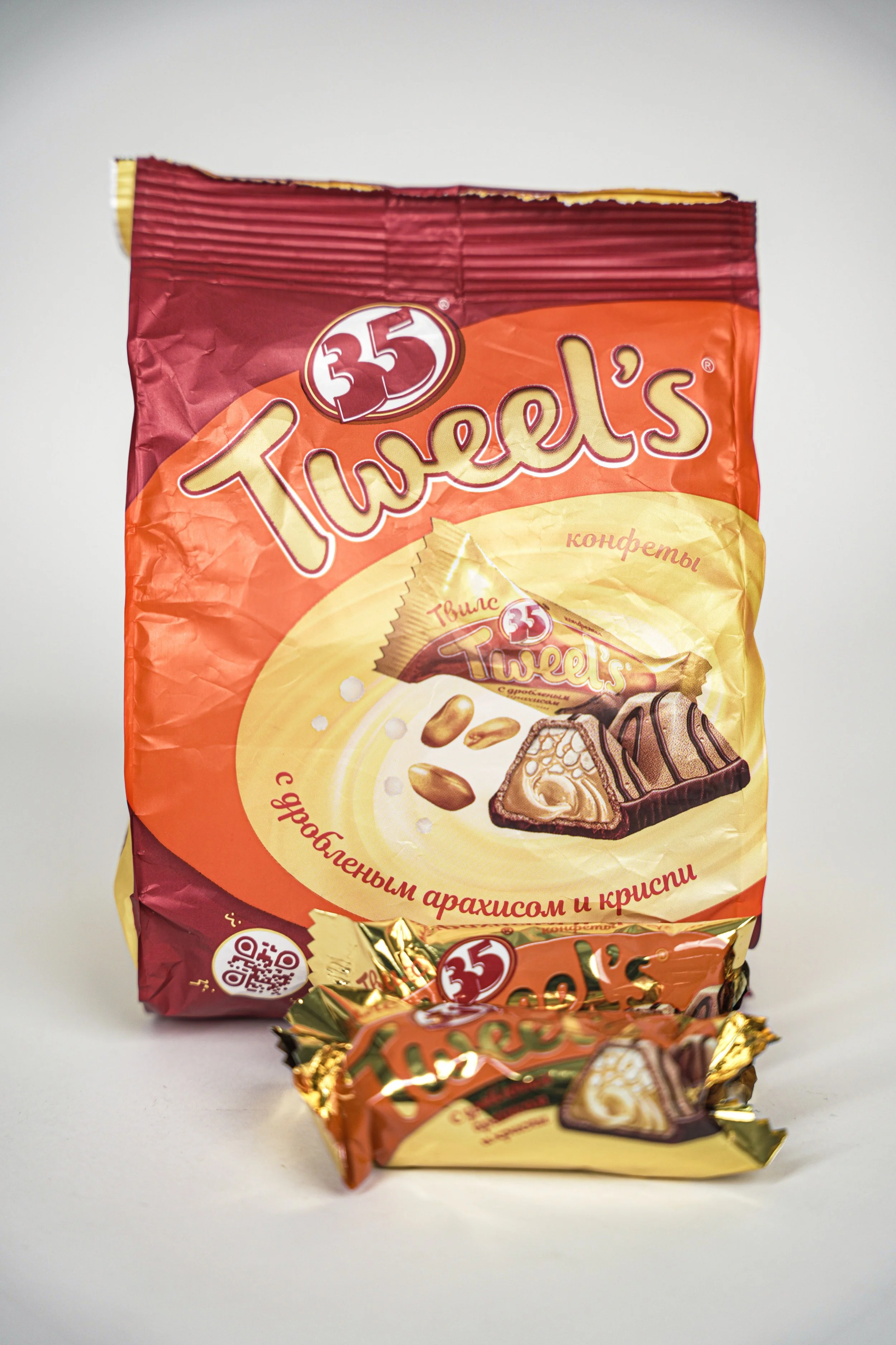 Twells candies with orange, yellow, and gold with images of candies and peanuts.