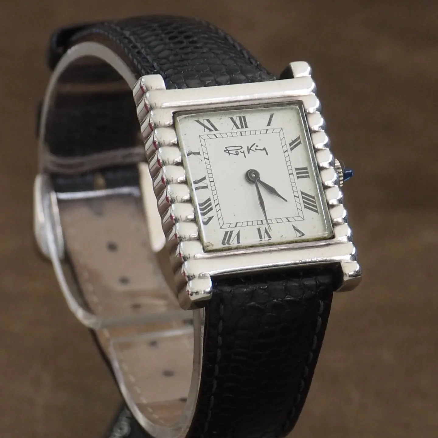 Roy King tank style watch with import marks dating it to 1975.
Really sharp case with stepped sides.

Dial has aged beautifully. Soft, even tone across it with the Roman numerals and blued hands still crisp. 

Cabochon crown, black leather strap, and