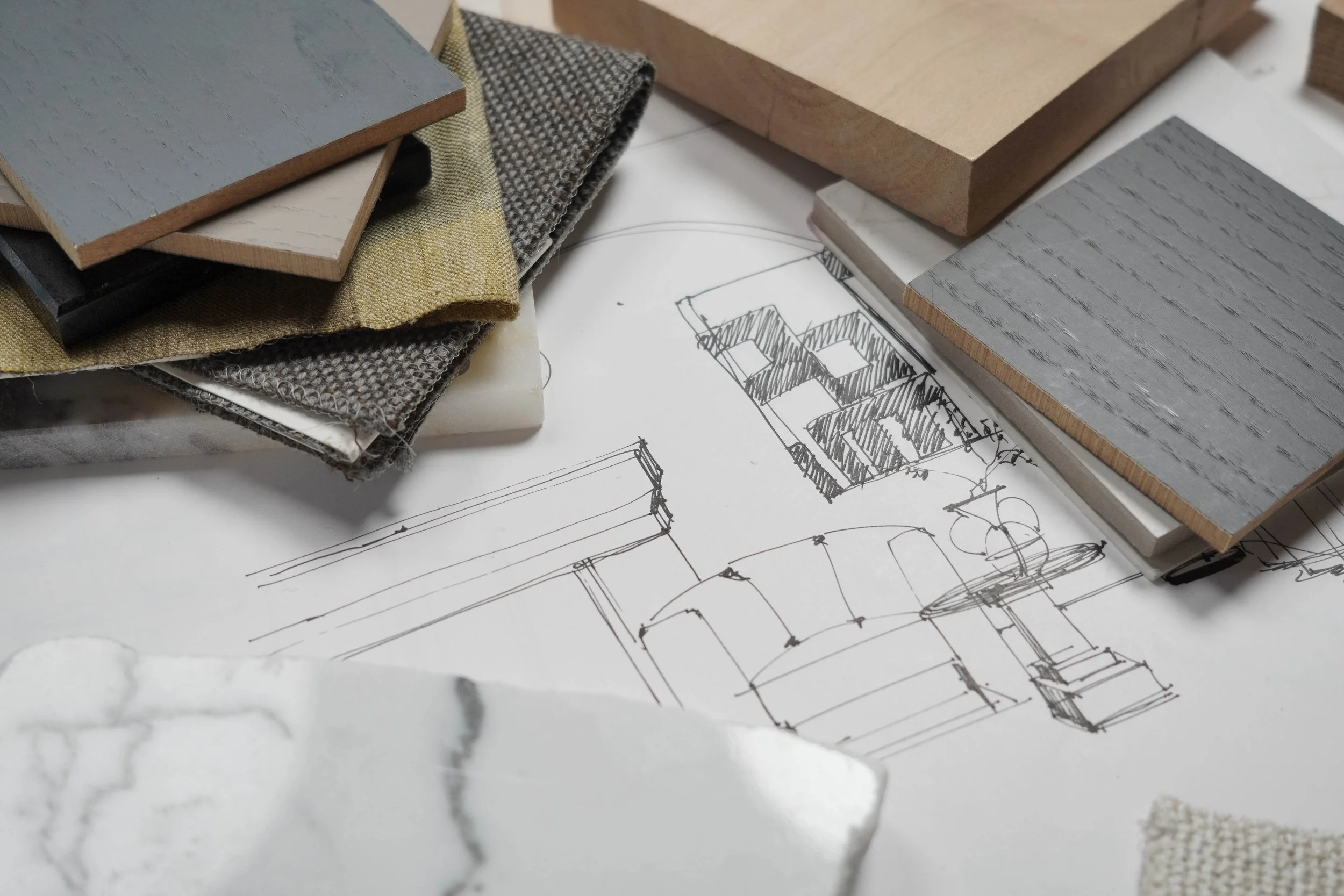 Samples of different wood and fabric materials placed on top of architectural sketches and sketches of furniture designs.
