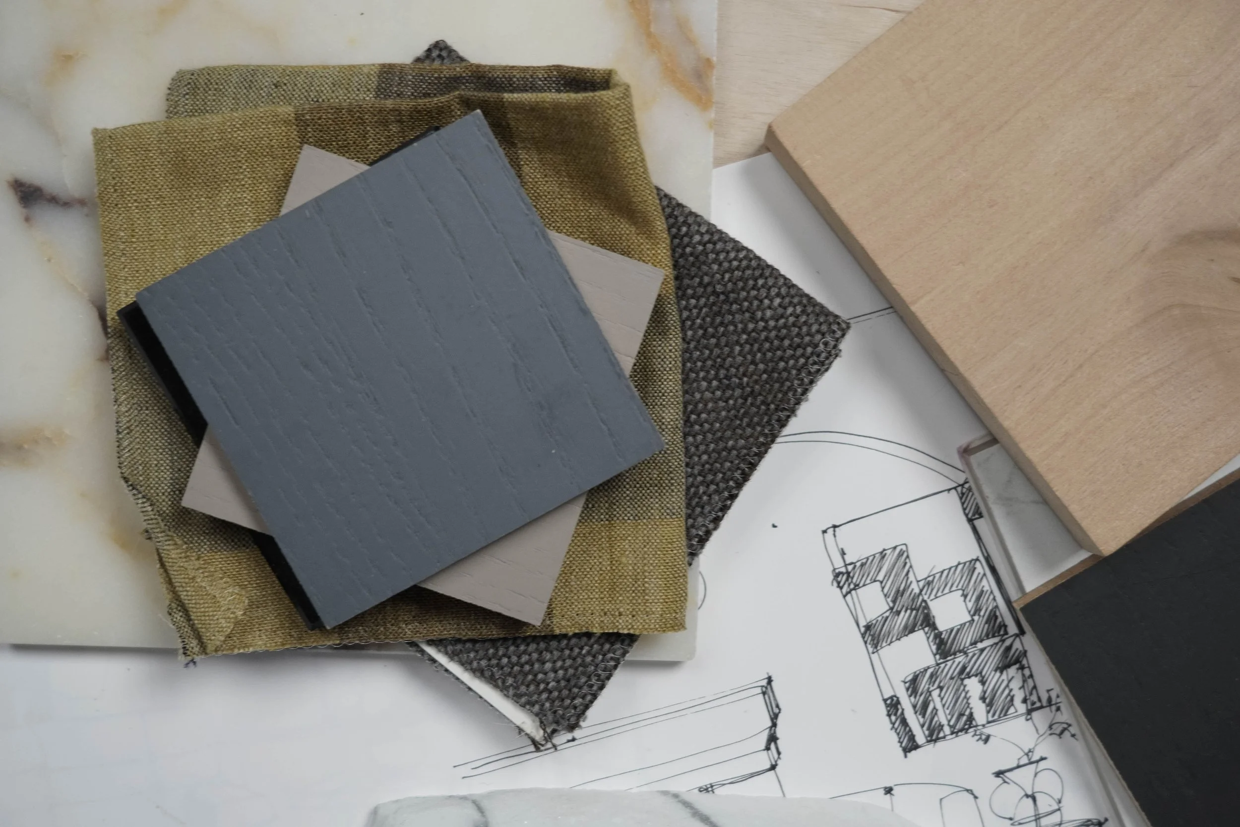 Samples of fabric and material swatches on a desk, alongside architectural sketches.