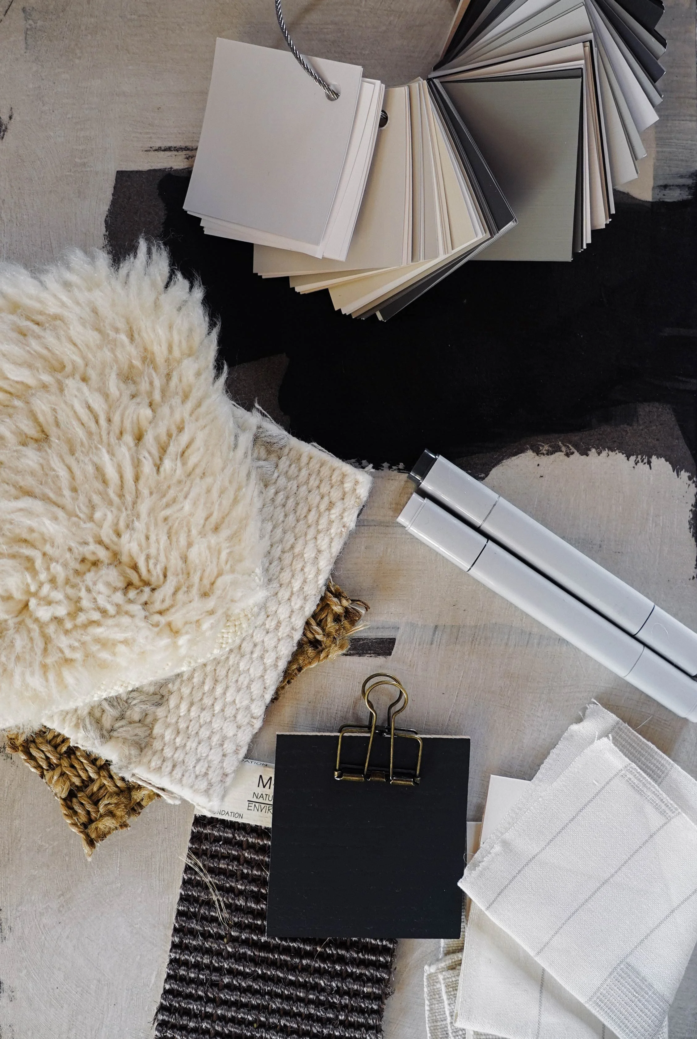 A collection of interior design and decorating materials, including fabric samples, color swatches, and samples of textiles, arranged on a wooden surface.