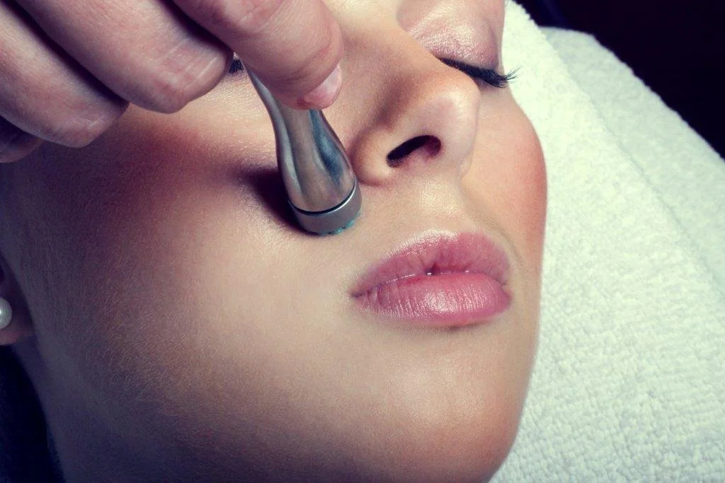 A woman receiving a DermaSweep resurfacing facial treatment in a spa setting.