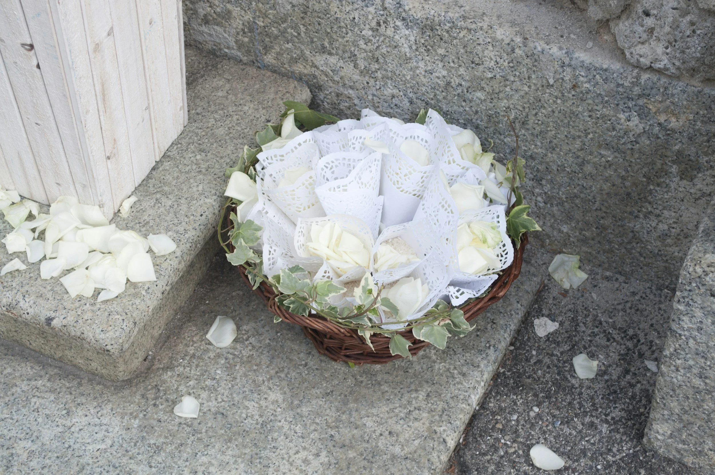 Ein Korb mit weißen Rosenblüten und Efeu auf Steinen, vermutlich bei einer Zeremonie