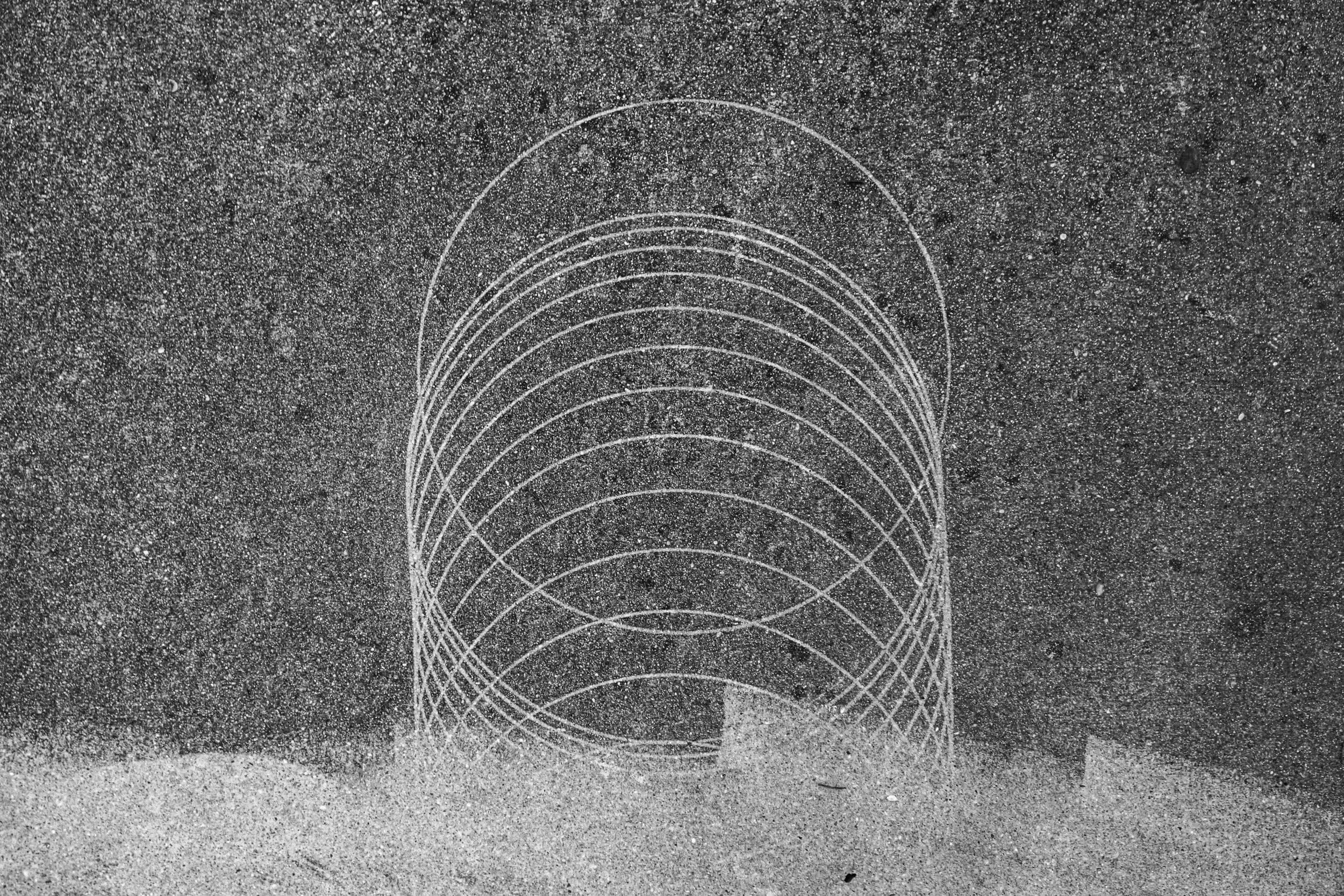 Sand mit weißen Linien, die in einem Kegel- oder Zylinder-Design angeordnet sind.