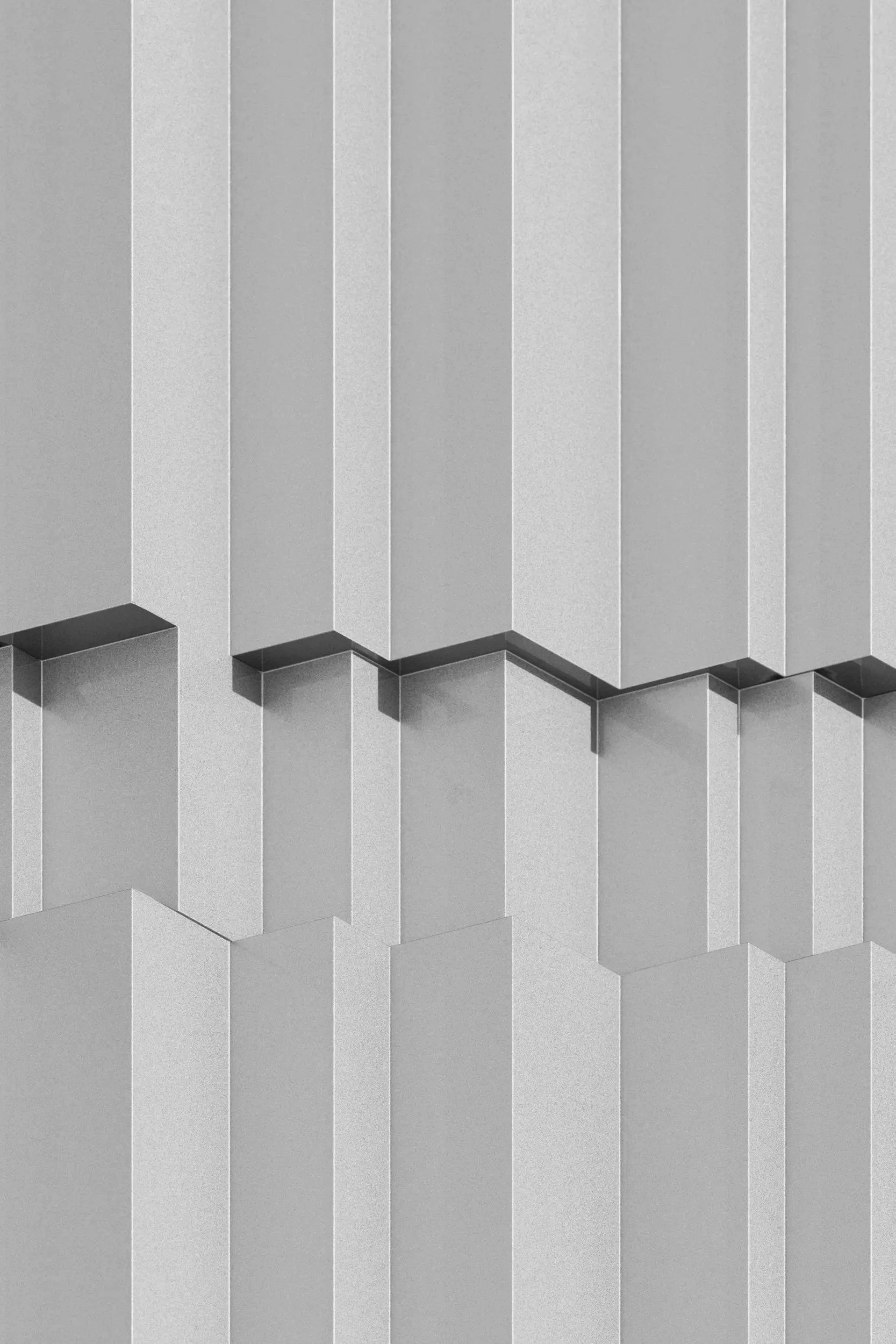 Fassade eines modernen Gebäudes mit geometrischen Mustern und Schatten, in Schwarz-Weiß