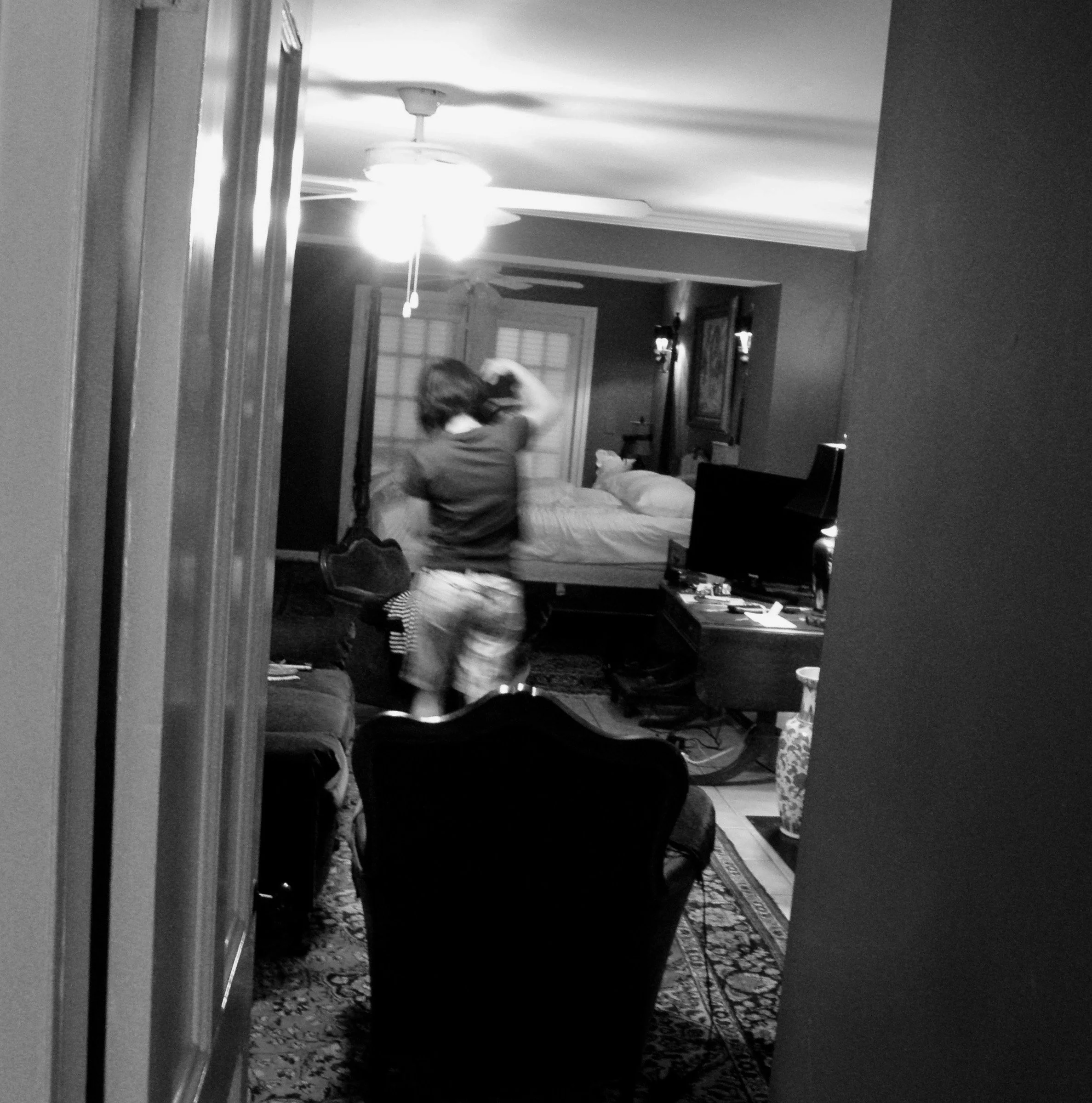 Ein Mann steht in einem Hotelzimmer, sieht zur Seite und hebt die Hand ans Haar.