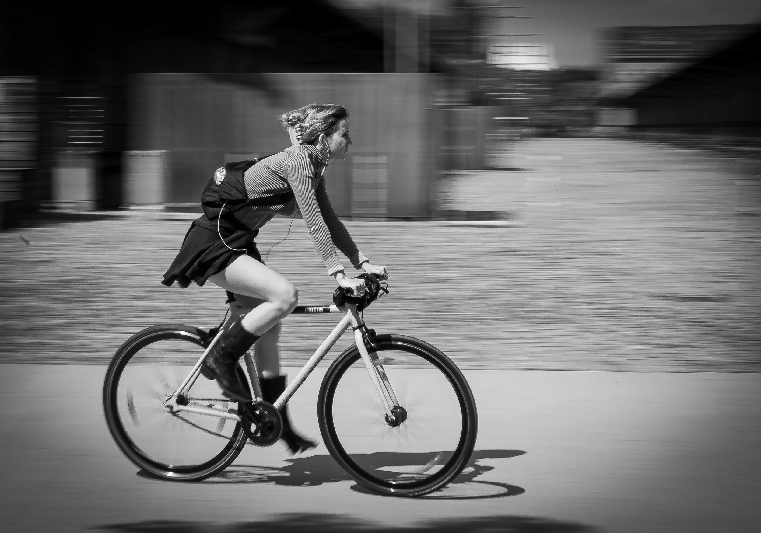 Schwarz-weiß Fotos eines Mädchens, das Fahrrad fährt, mit Wind im Haar, auf der Straße, mit schnellem Bewegungsunschärfe-Effekt.
