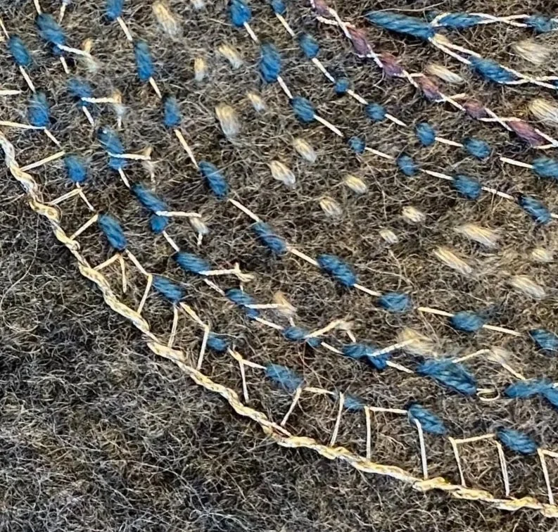 Nahaufnahme eines Stickarbeit auf grauem Filz.