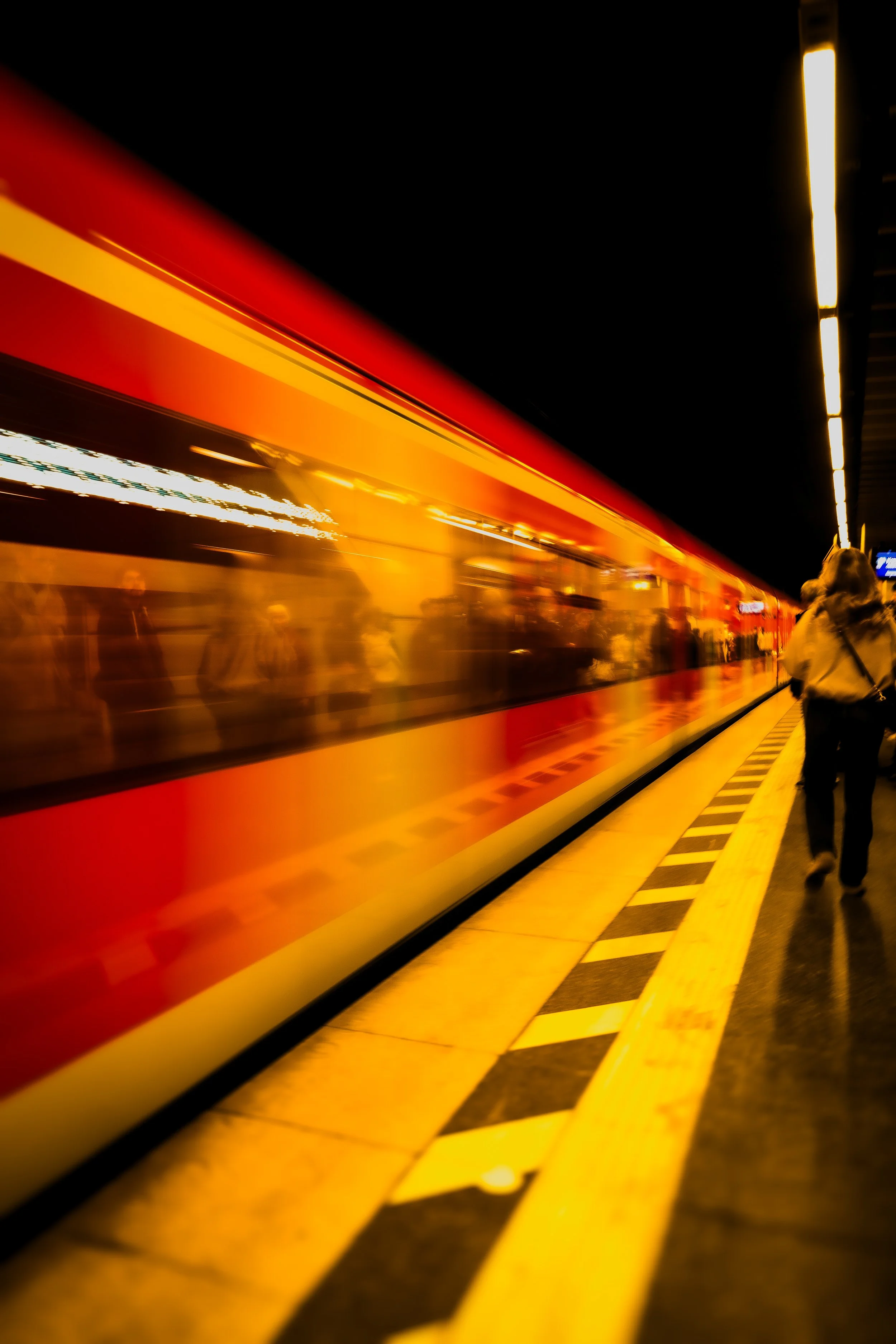 Ein Zug fährt durch einen U-Bahnhof bei Nacht, die Bewegungsunschärfe lässt die Lichter und den Zug schnell erscheinen.