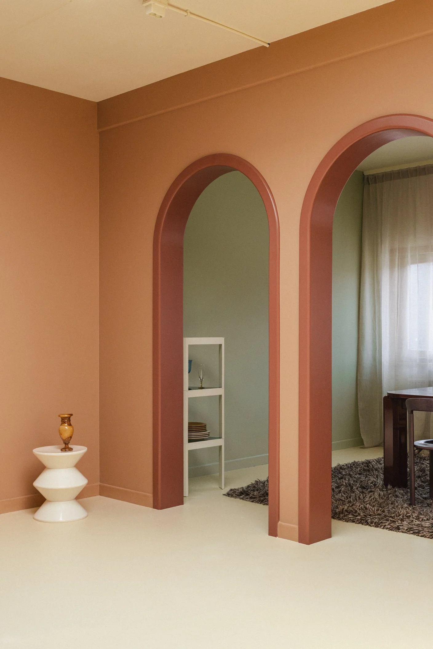 Kleurrijke daglichtstudio met warm beige vloer en twee bogen. Op de muur zit een warme caramel kleur en een saliegroene kleur.