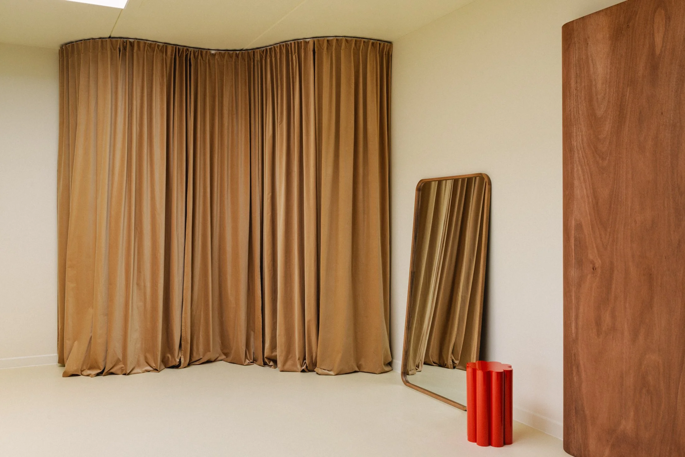 Een kamer met beige gordijnen, een spiegel en een houten menubord.