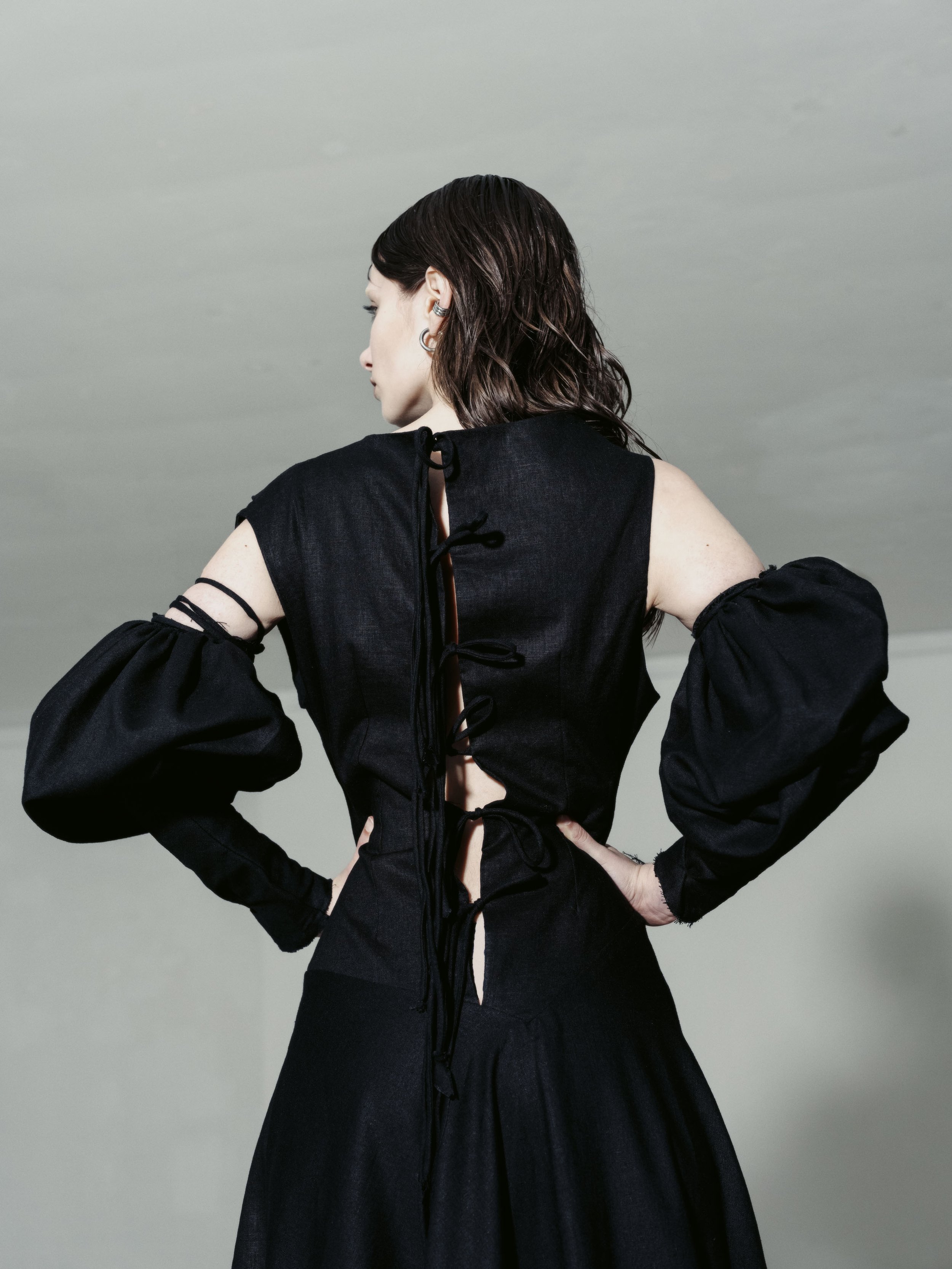 Frau in schwarzem Kleid mit Cutouts und Schnürung auf dem Rücken, seitlich fotografiert