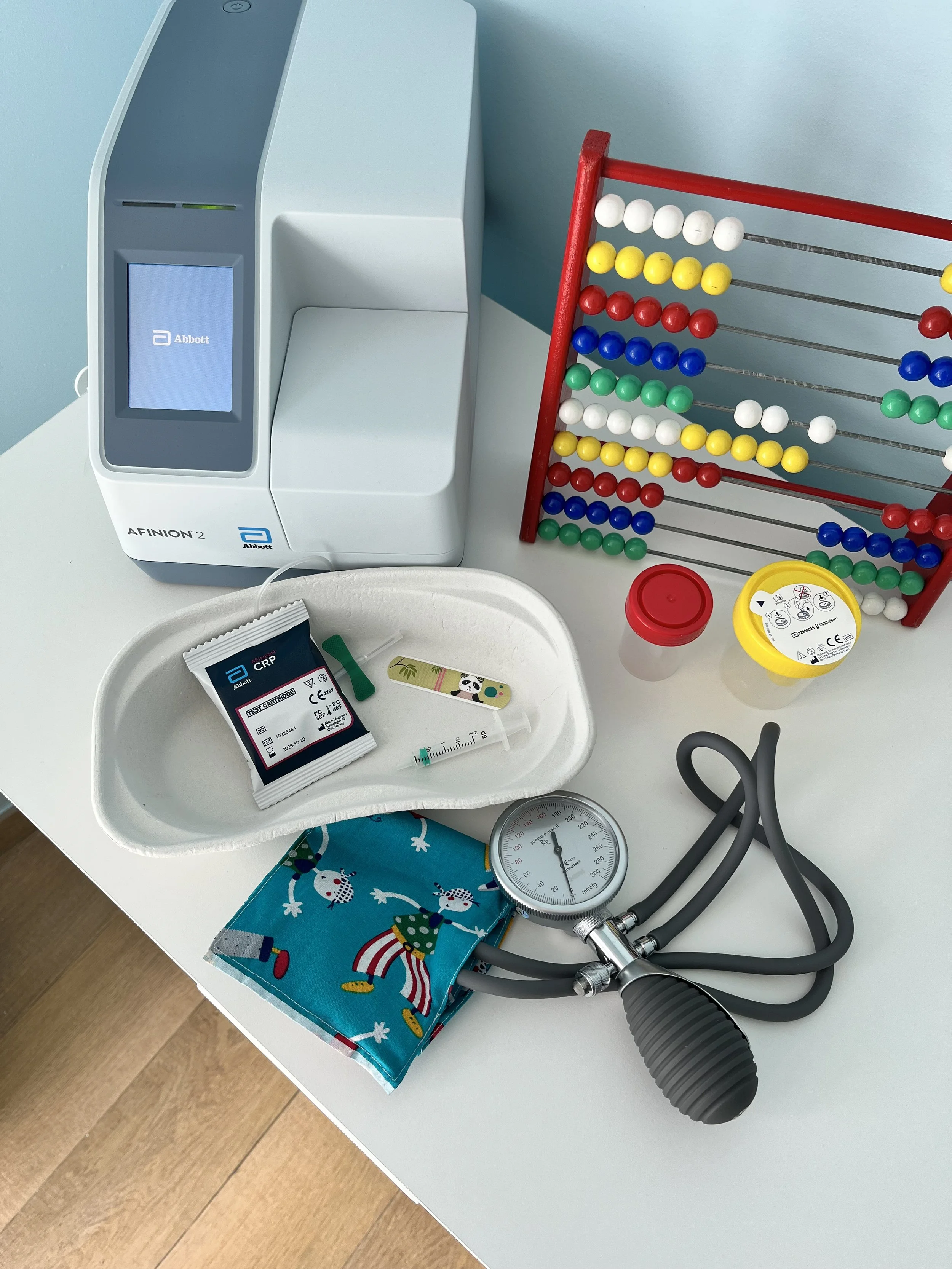 Huisartspraktijk met medische uitrusting, zoals een bloeddrukmeter, een stethoscoop, een spuit, medicatie, een peiling en een apparaat voor labtesten en monitoren.