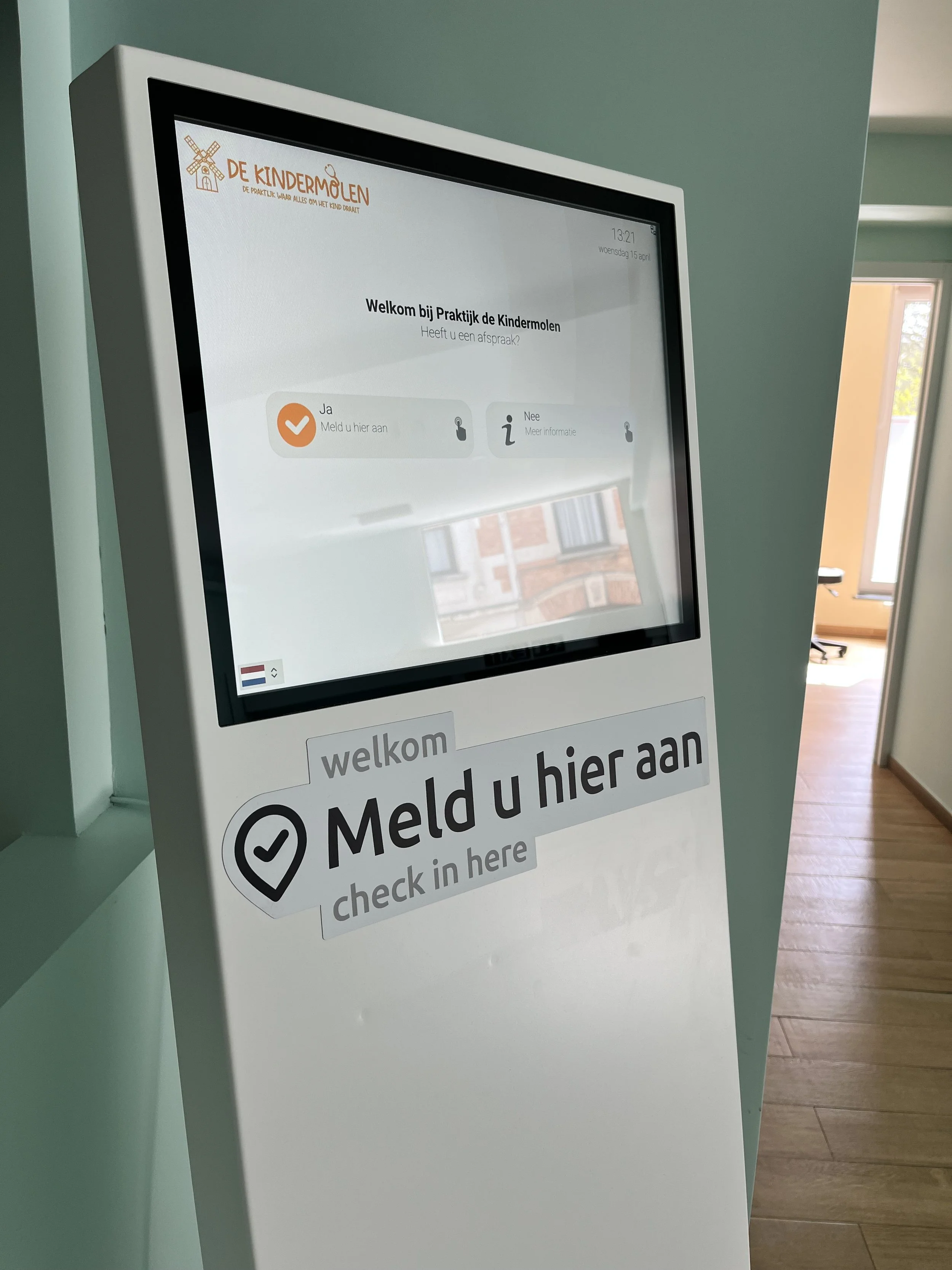 Touchscreen check-in kiosk for 'De Kindermolen', a children's practice or dental practice, with text asking to check-in and options for 'Yes' and 'No'.