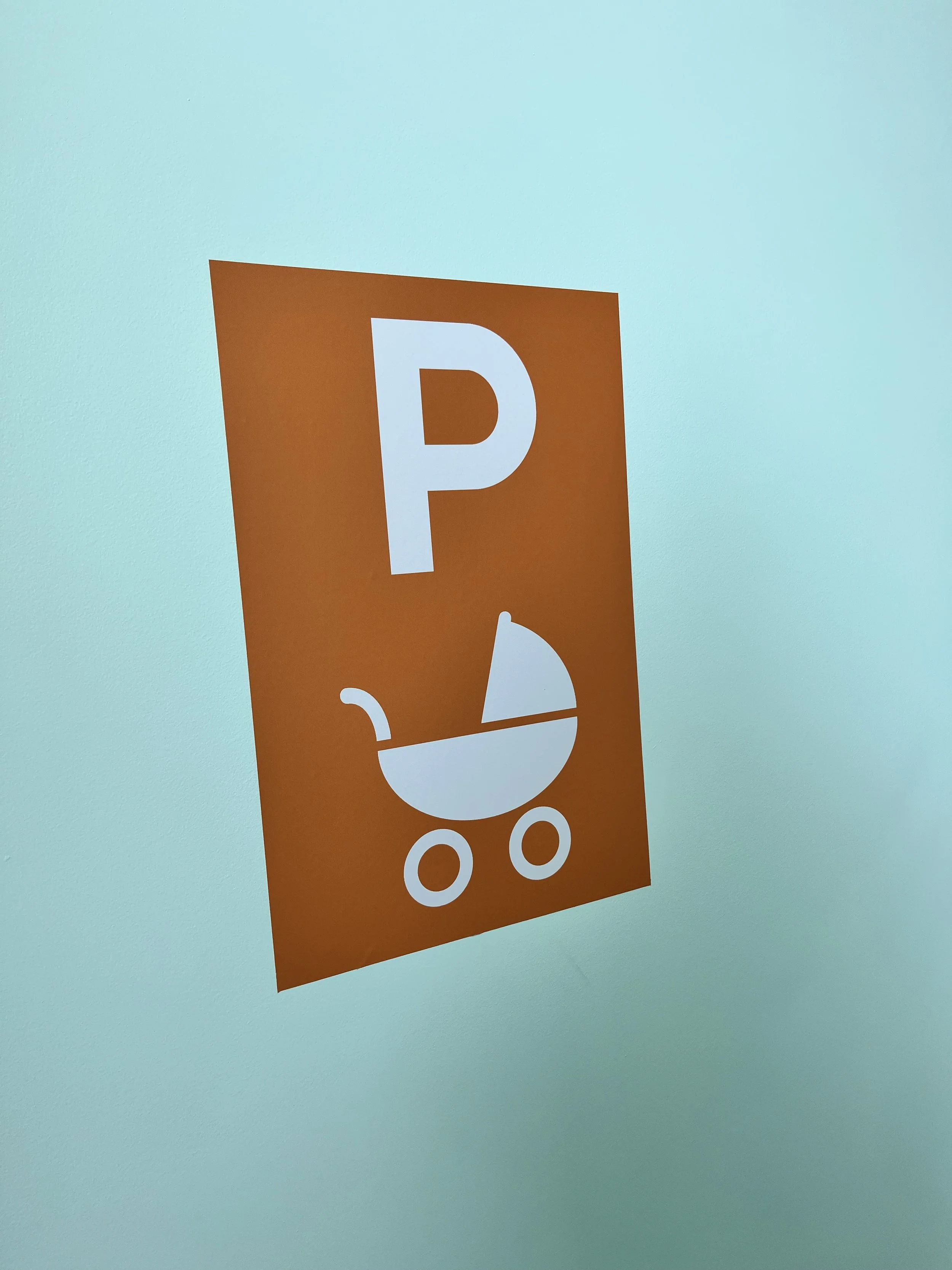 Een oranje parkeerbord met een witte afbeelding van een kinderwagen en een witte letter P