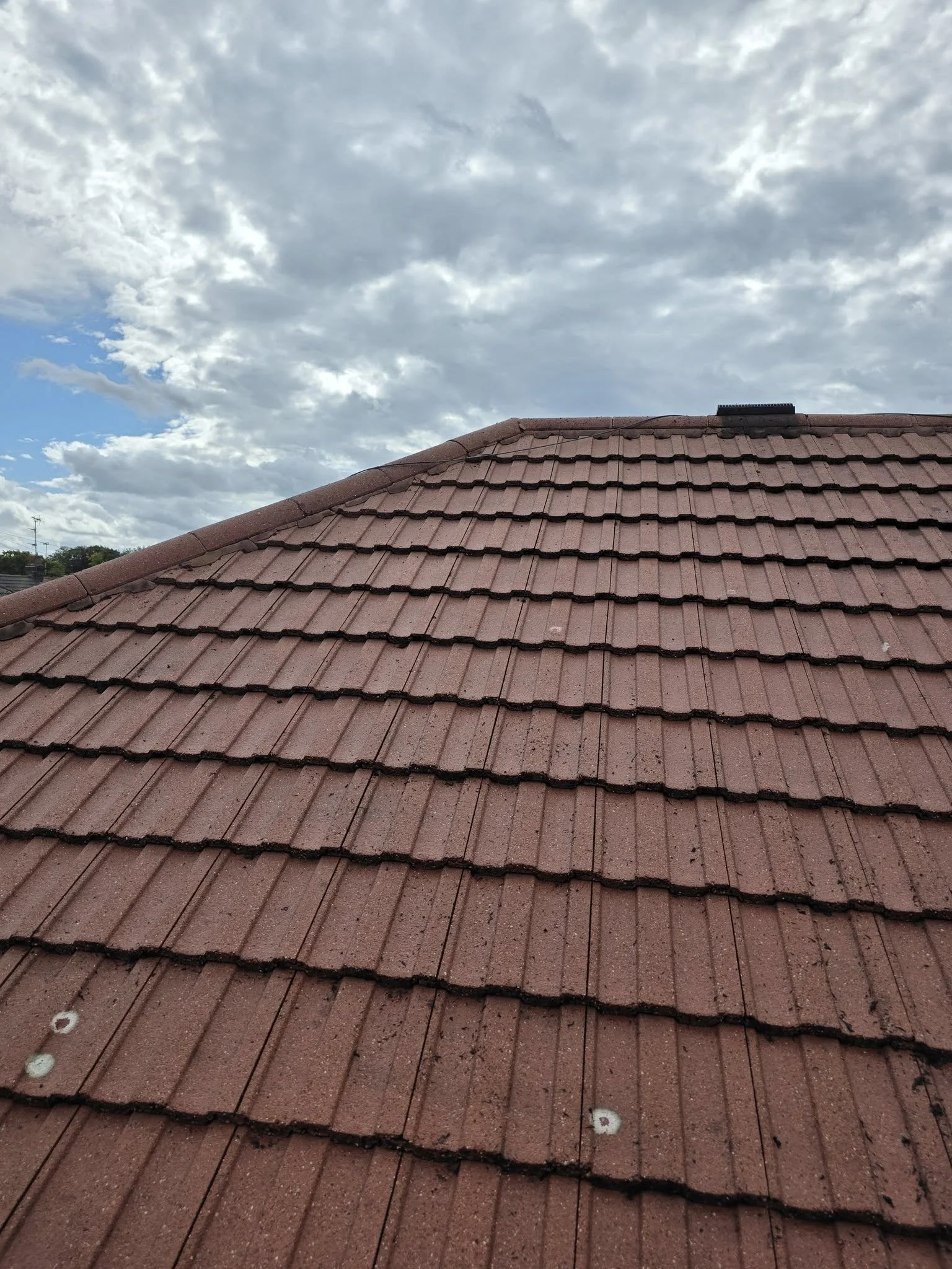Close-up of a rooftop with decorative white spiked finials, showing before and after cleaning comparison. The cleaned section appears brighter and free of dirt. a star window cleaning services.