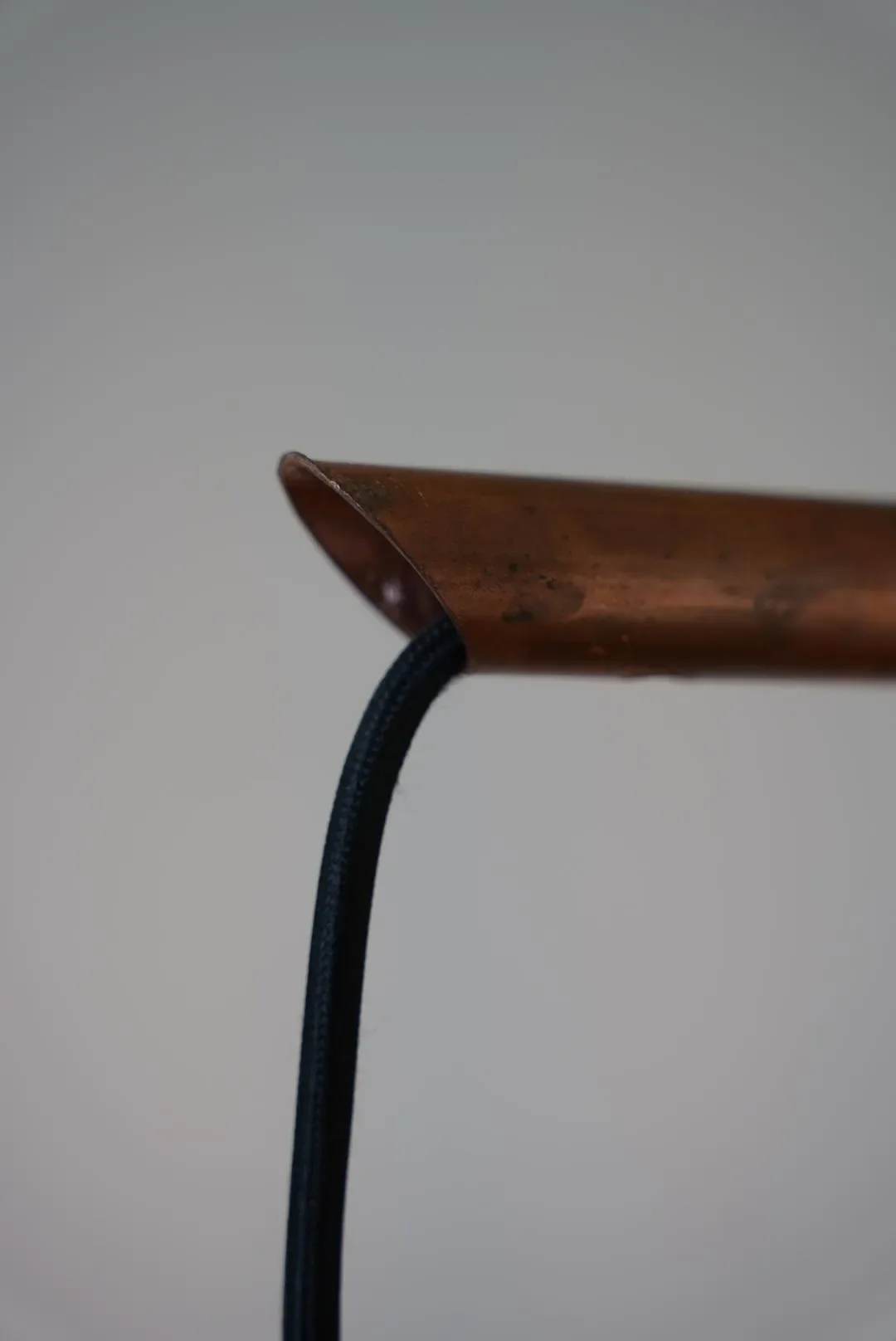 Close-up of a wooden table with a black cord hanging off the side against a plain background.