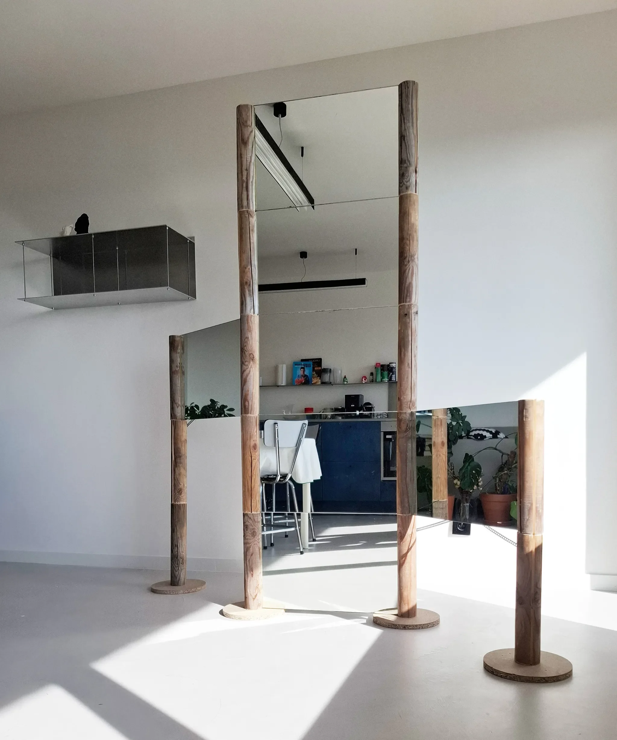 A large wooden freestanding mirror with four vertical poles in a minimalist modern apartment.
