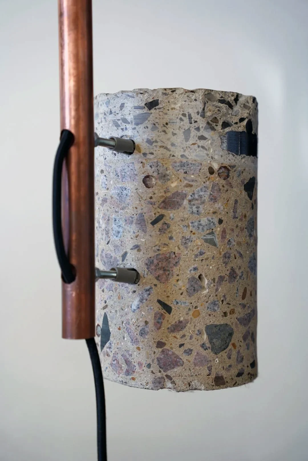 Close-up of a textured cylindrical object mounted on a stand with copper and black metal parts.
