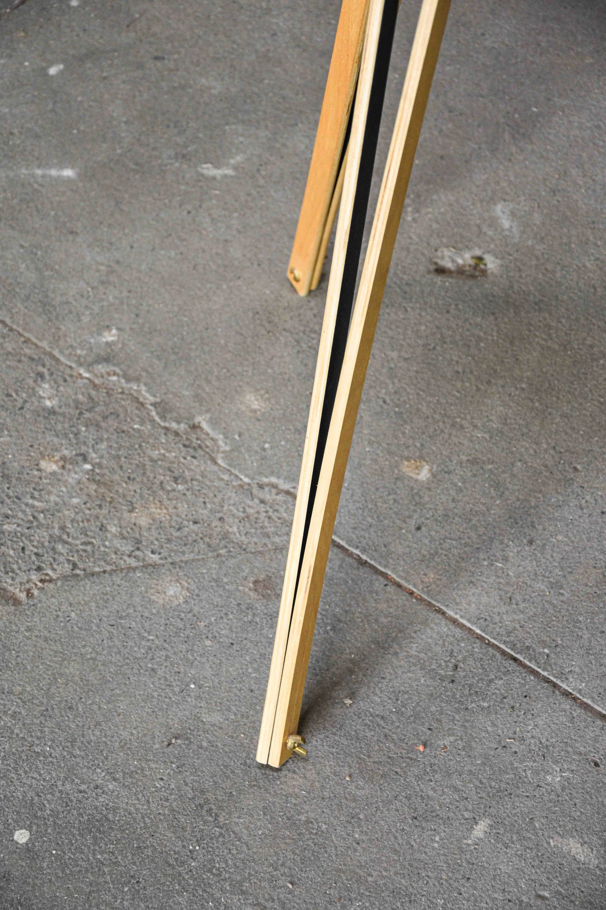 Wooden and metal ruler standing on concrete ground.