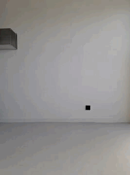 Empty white room with a black outlet on the wall and a wall-mounted air conditioning unit.