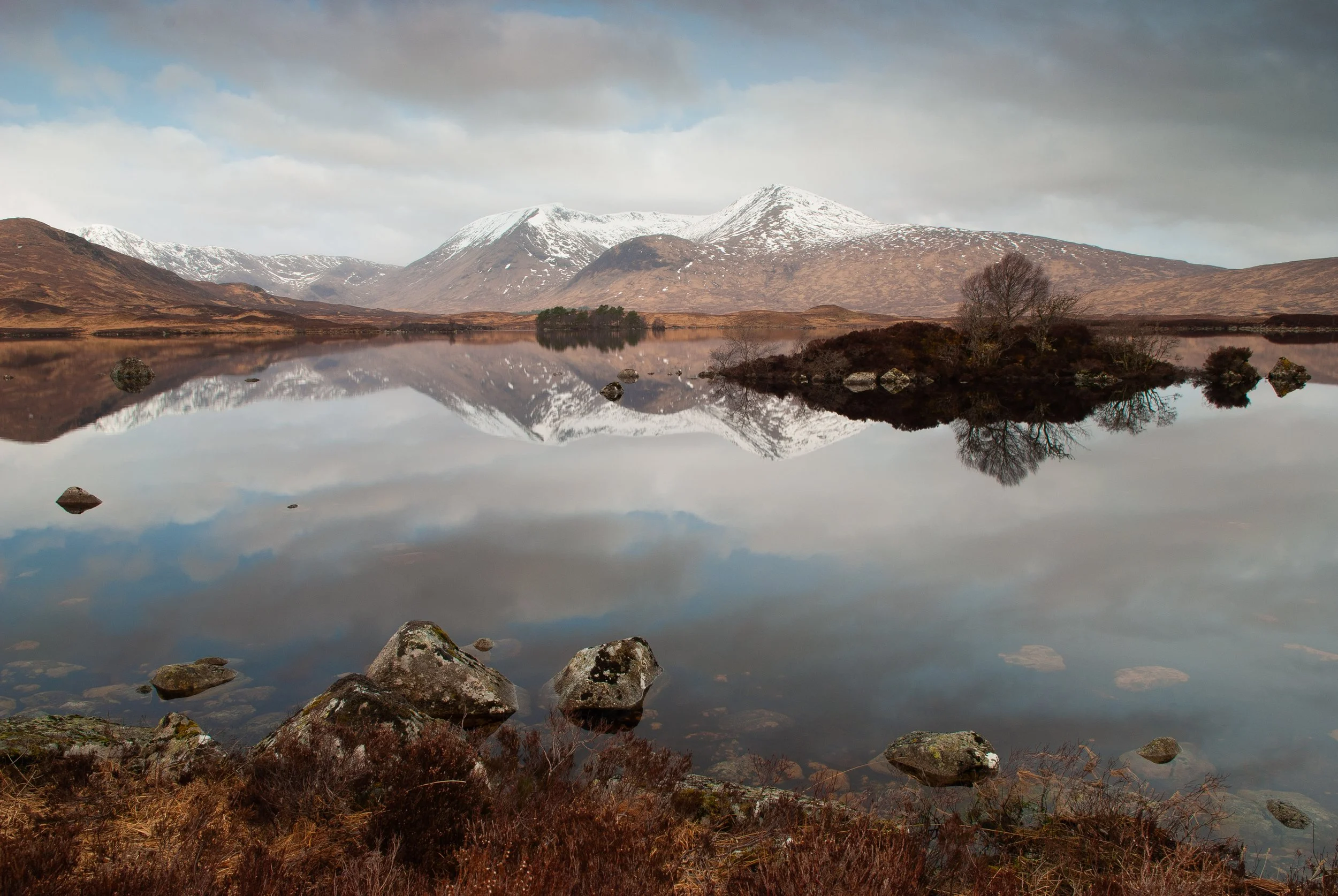 Snow-capped mountains reflected in loch, Glencoe, Scottish Highlands