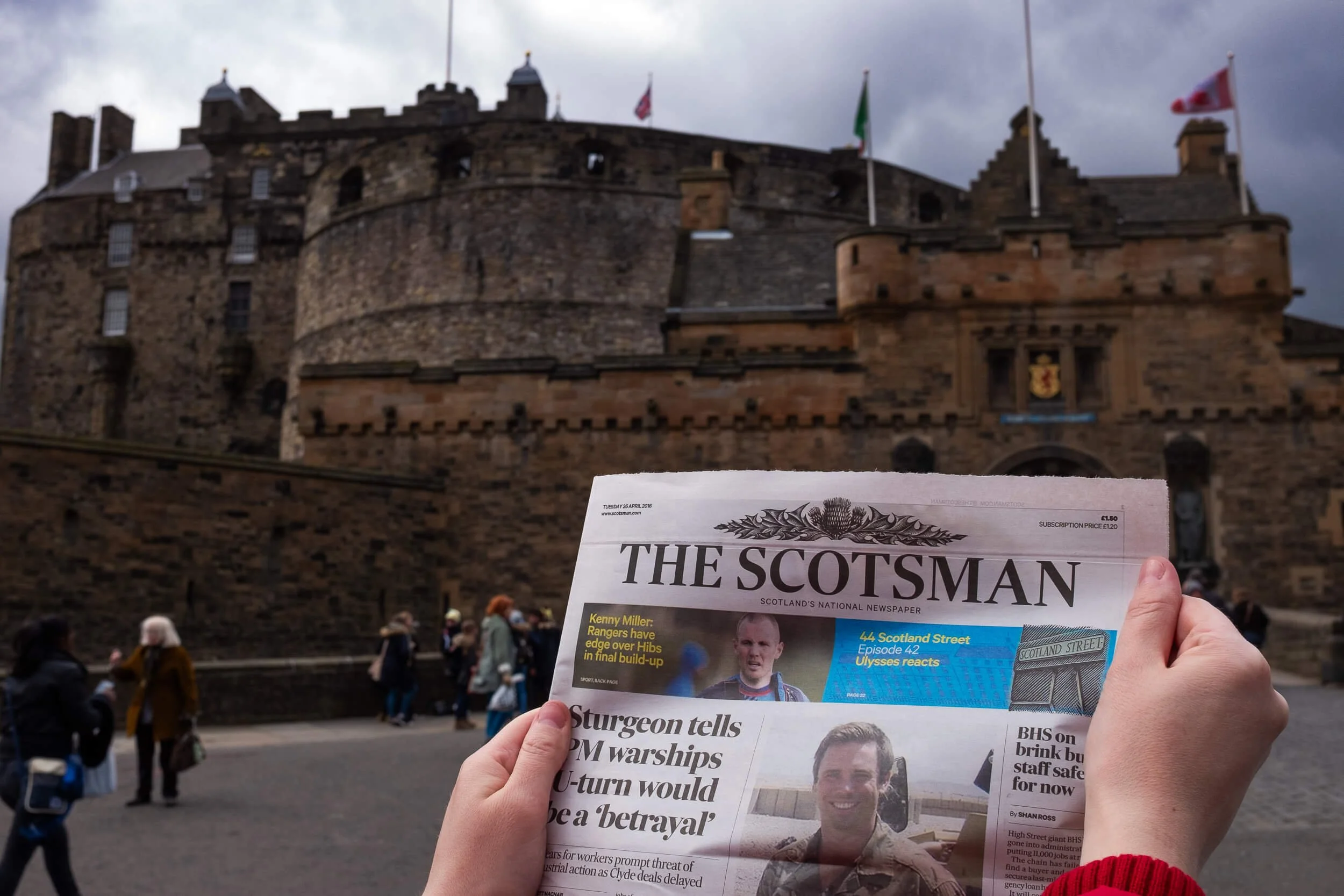 The Scotsman newspaper held up outside Edinburgh Castle on a wedding morning — documentary wedding photography Scotland