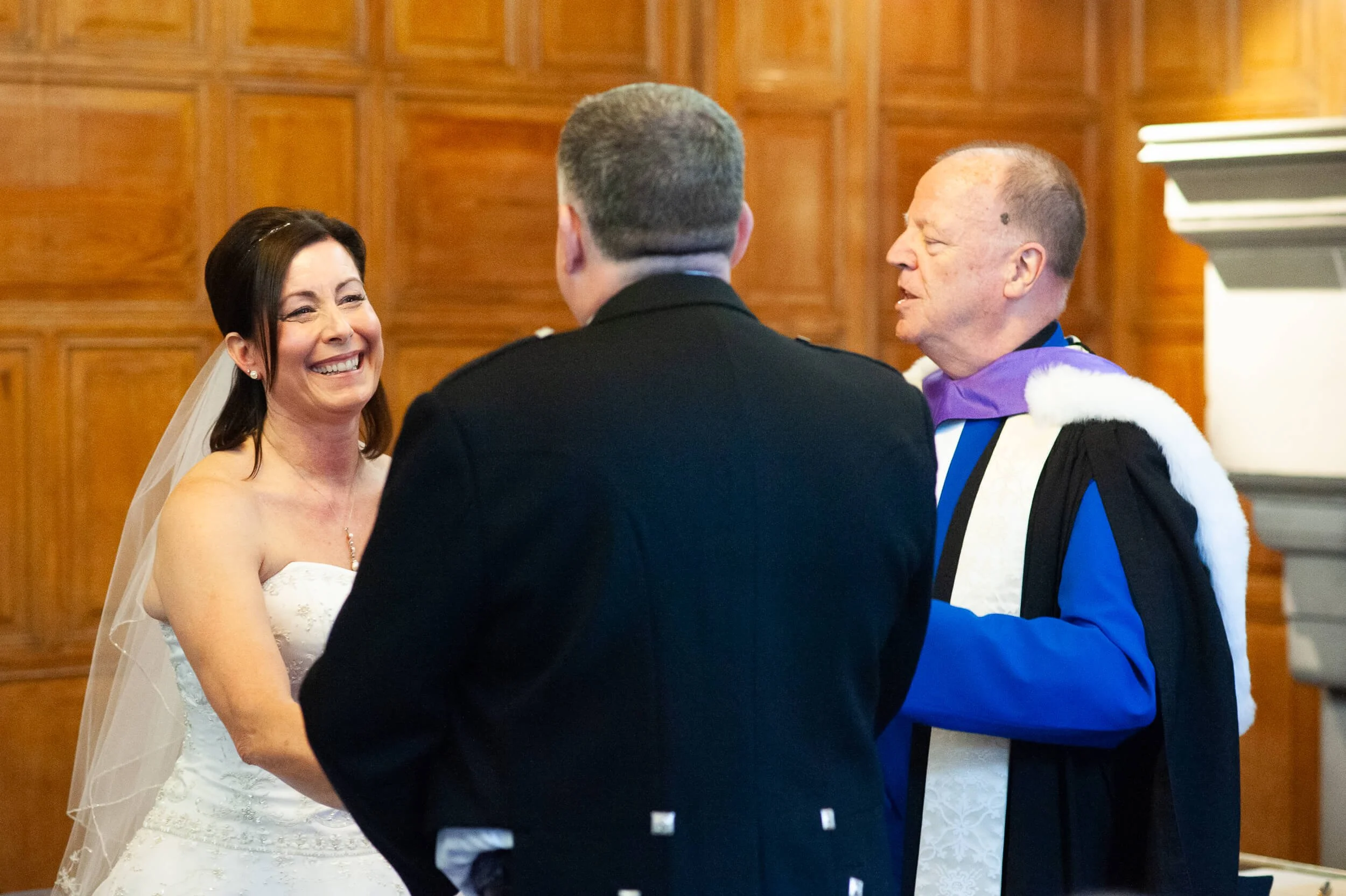 Alt text:  Bride laughing during civil wedding ceremony at Edinburgh Castle — candid documentary wedding photography Scotland