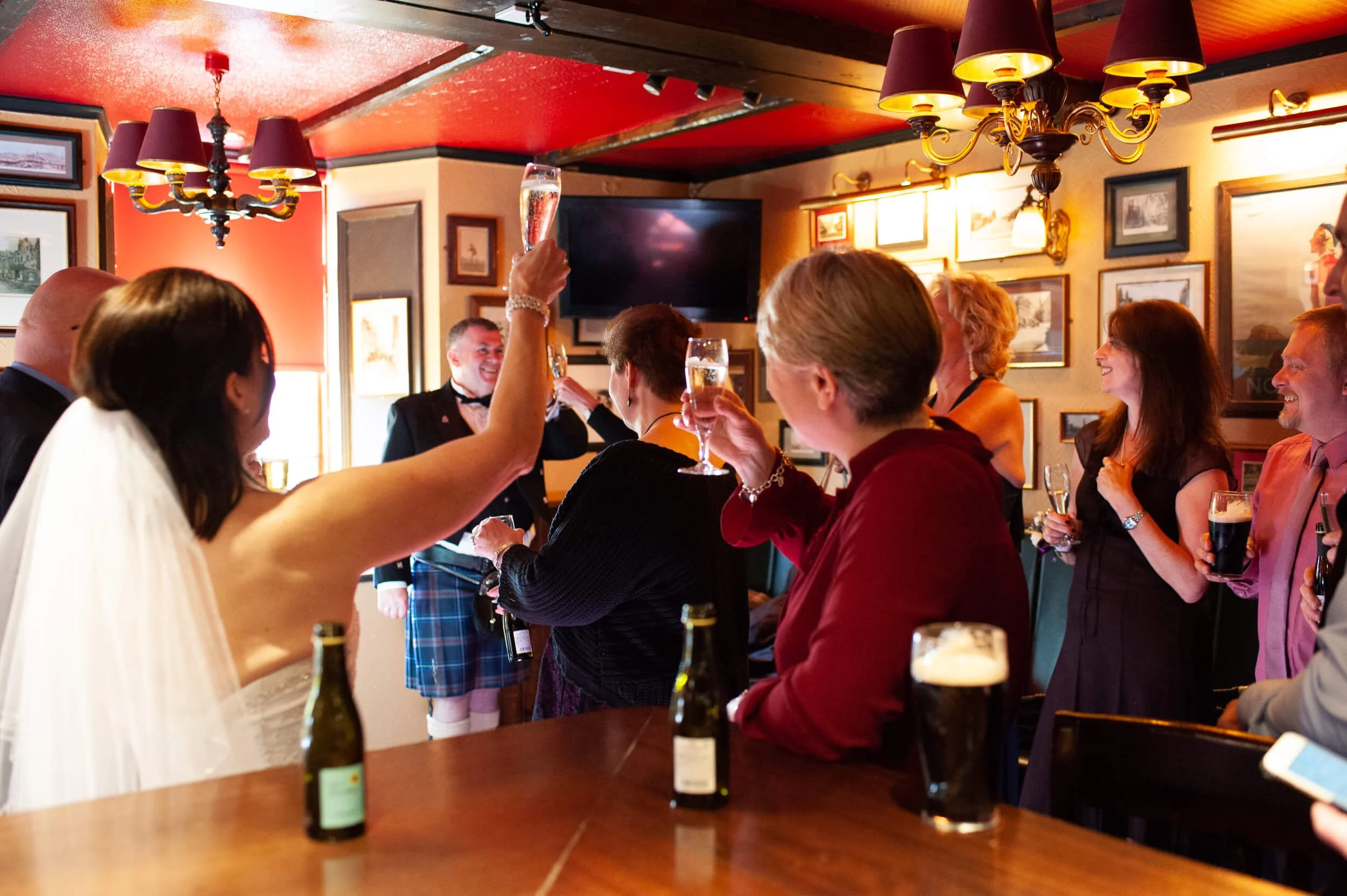 Bride toasting with wedding guests in a traditional Edinburgh pub — documentary wedding photography Scotland