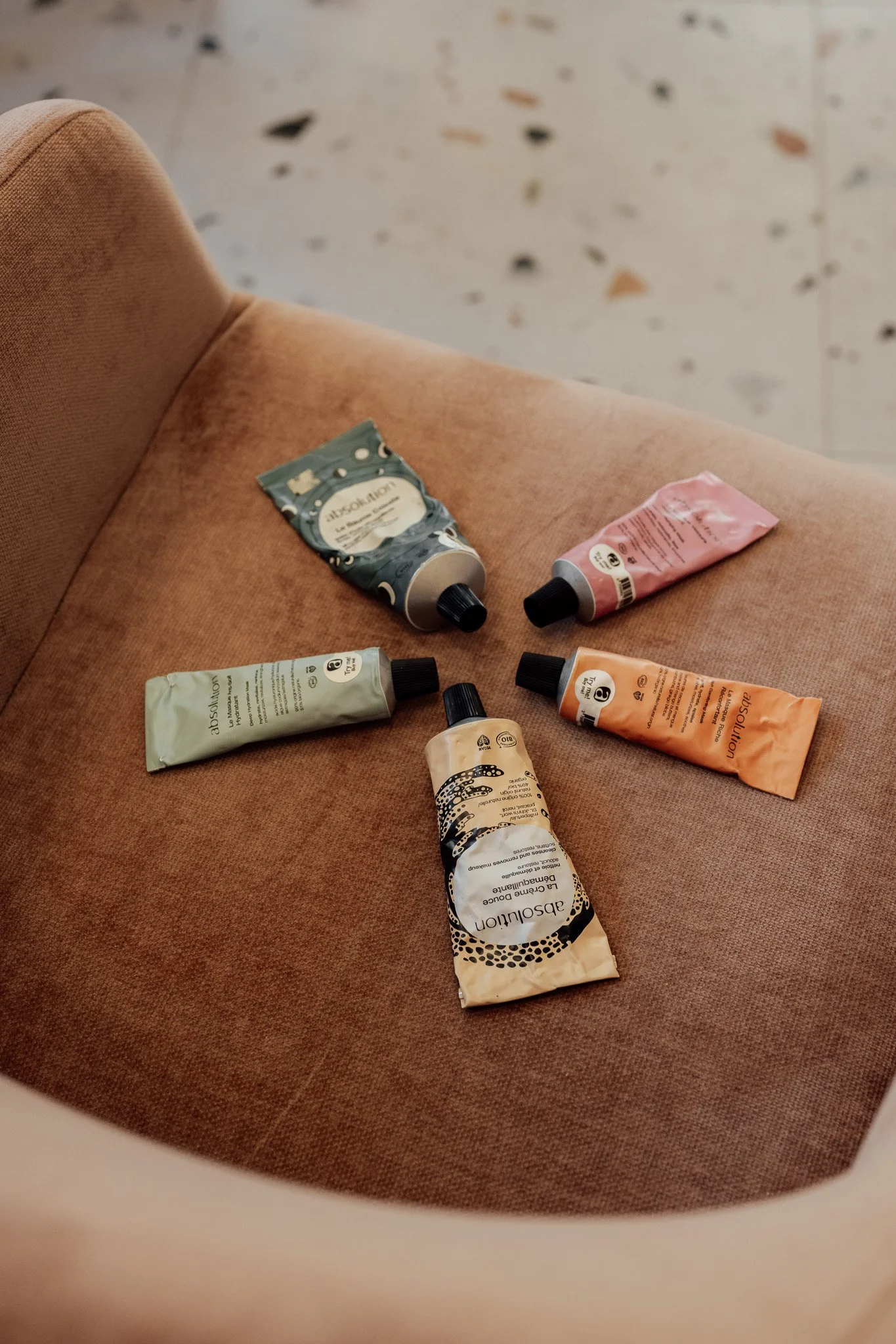 Différents tubes de crème ou de lotion posés sur un siège en tissu orange