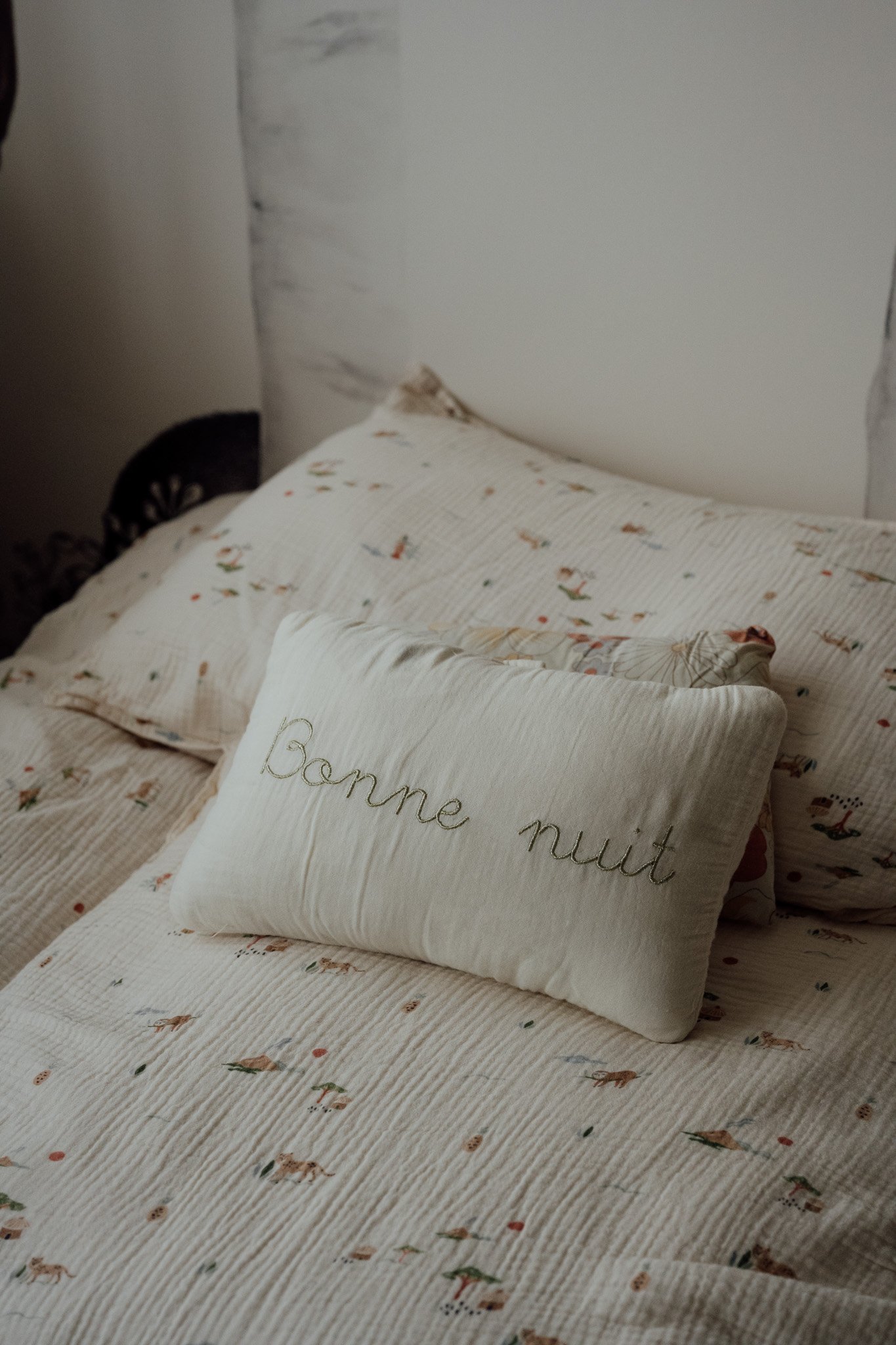 Un lit avec des oreillers, dont un avec l'inscription en français 'Bonne nuit'