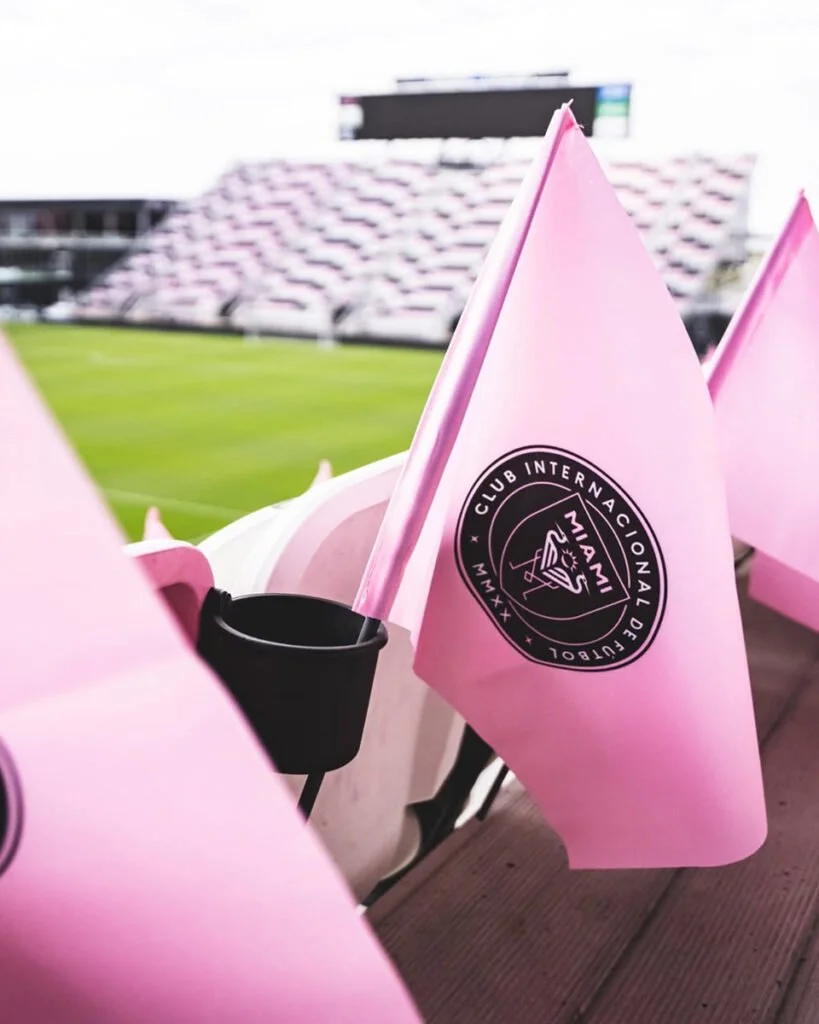 Pink flags with the logo of Club Internacional de Fútbol Miami, displayed at a sports stadium.