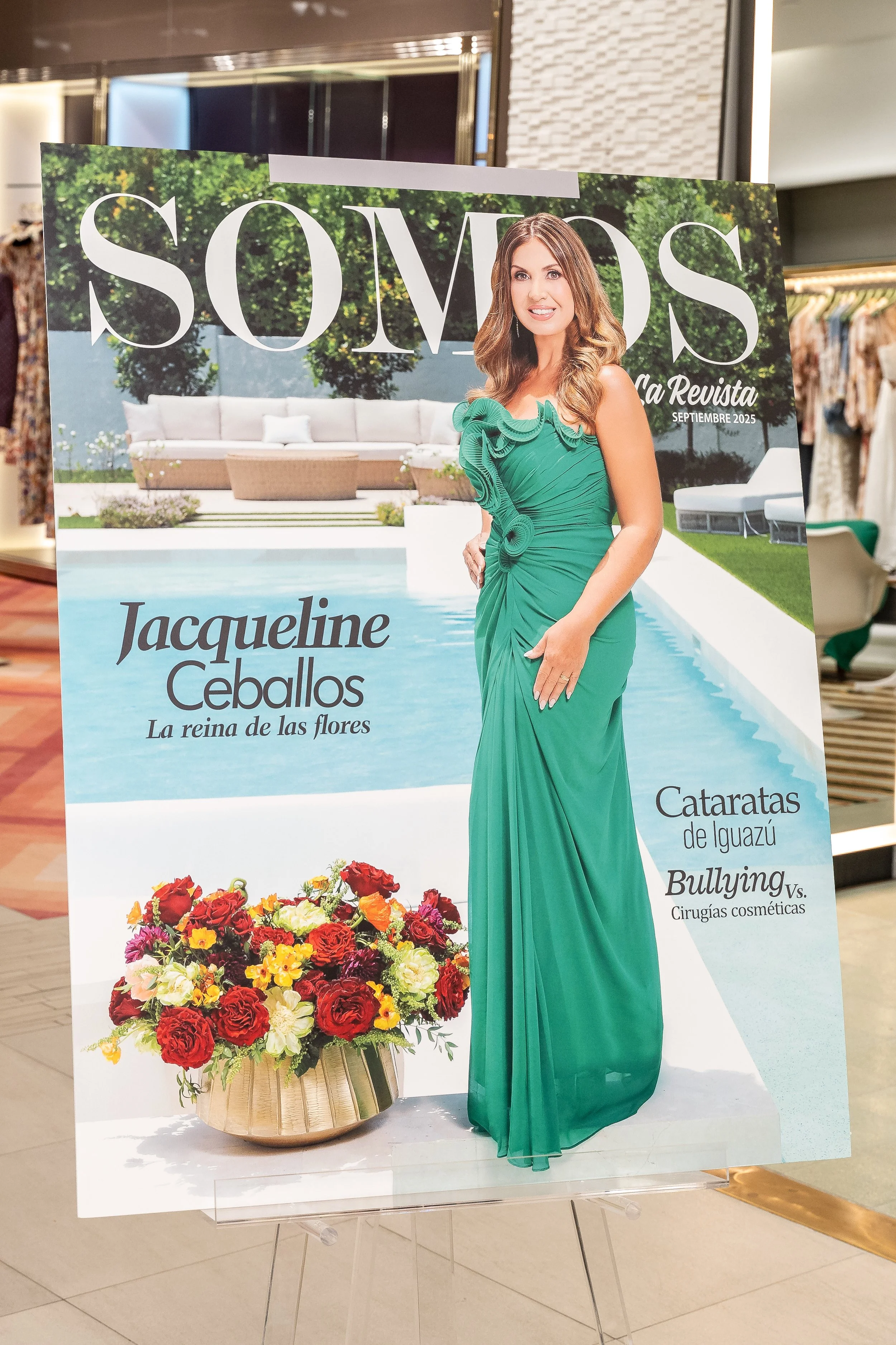 Magazine cover featuring Jacqueline Ceballos in a green dress, standing next to a floral arrangement, with outdoor furniture and pool in the background.