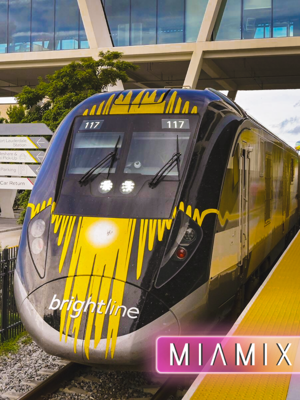A Brightline train at a station with a black and yellow exterior design and the Brightline logo on the front, with two people visible inside the train.