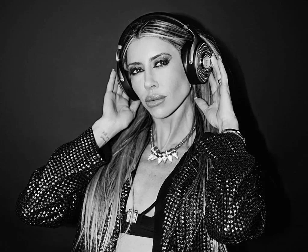 Black and white photo of a woman wearing headphones and a studded jacket, looking at the camera.