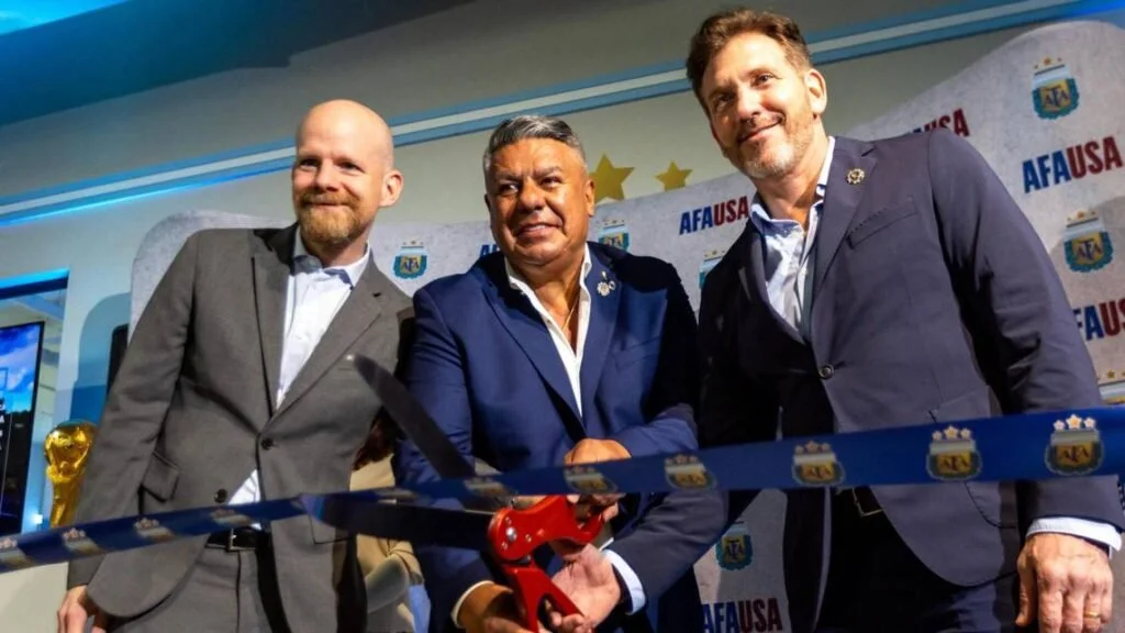 Three men in suits at a ribbon cutting ceremony at a sports event, with AFA USA banners in the background.