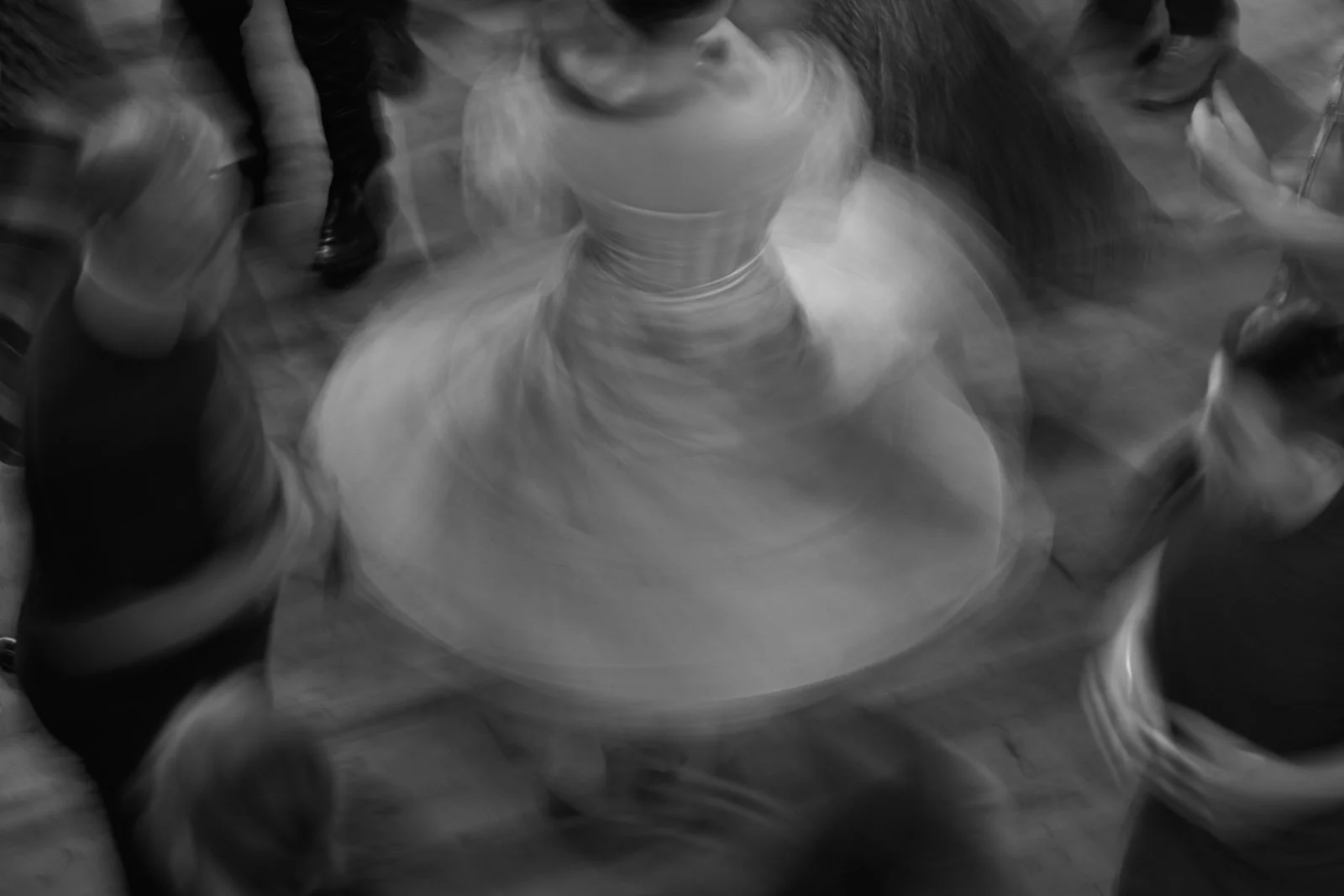 A blurred black and white photo of a person spinning on a dance floor.