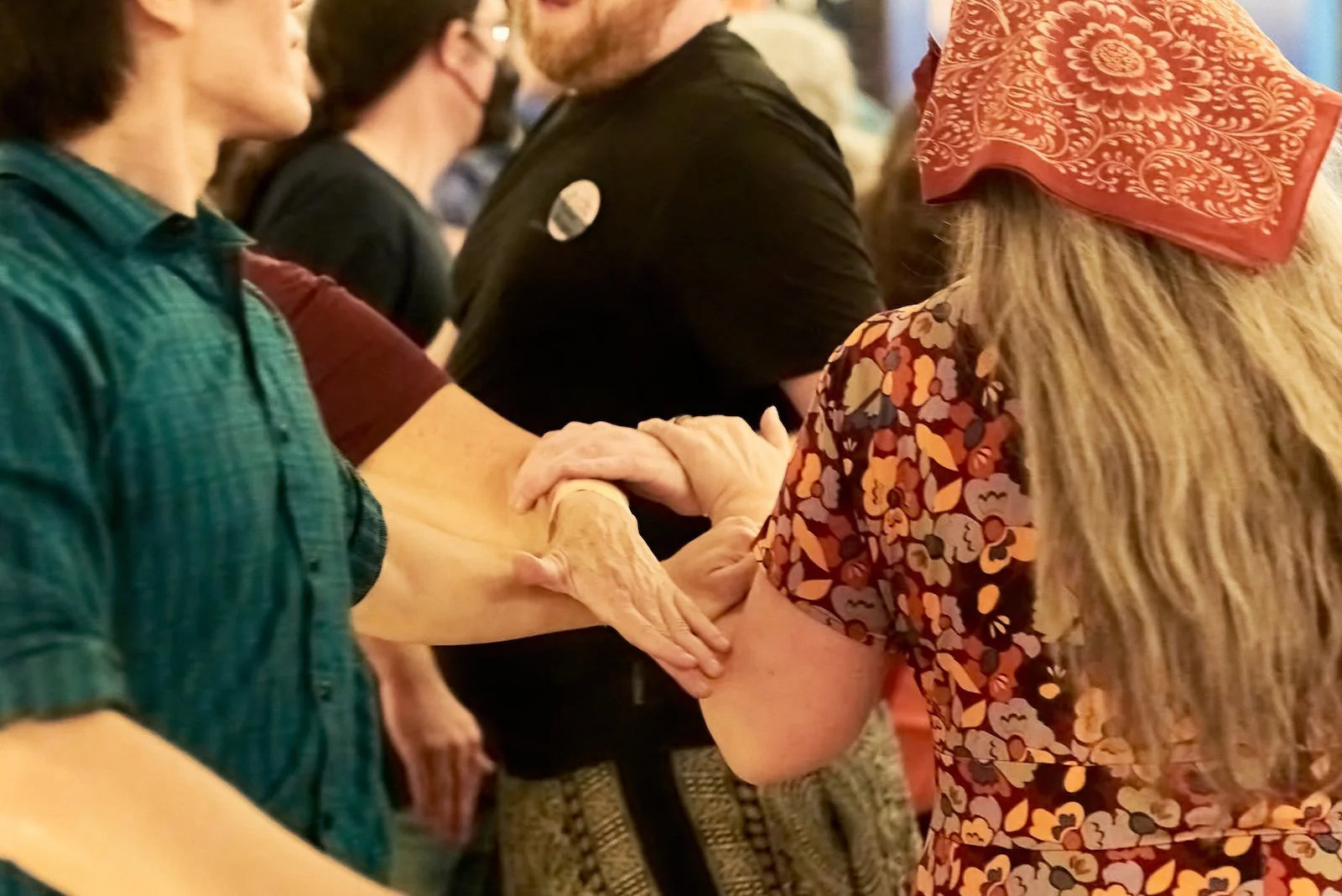 People holding and supporting each other's hands in a line, during a contra dance.