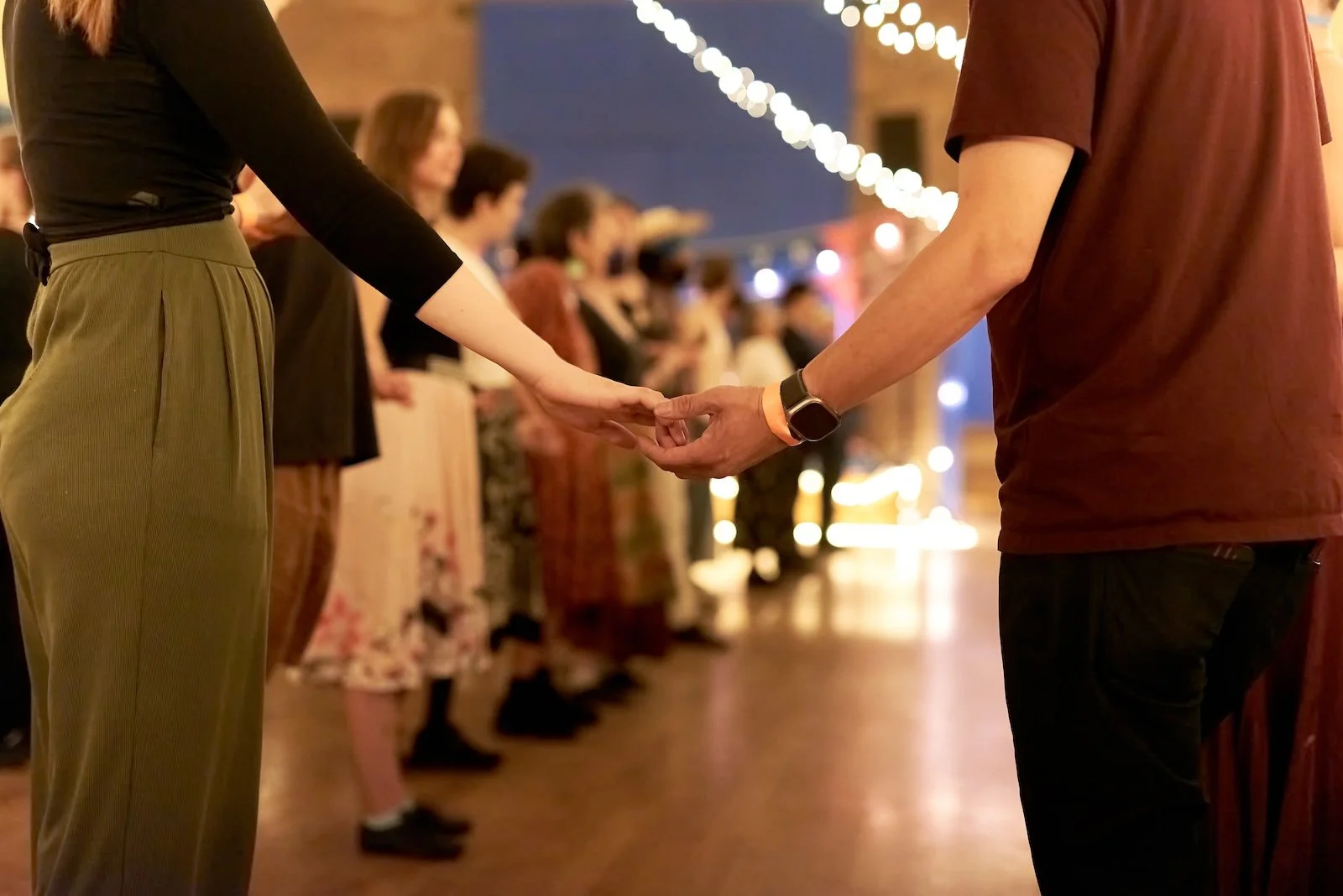 A close-up of a couple holding hands during a wedding ceremony with guests in the background.