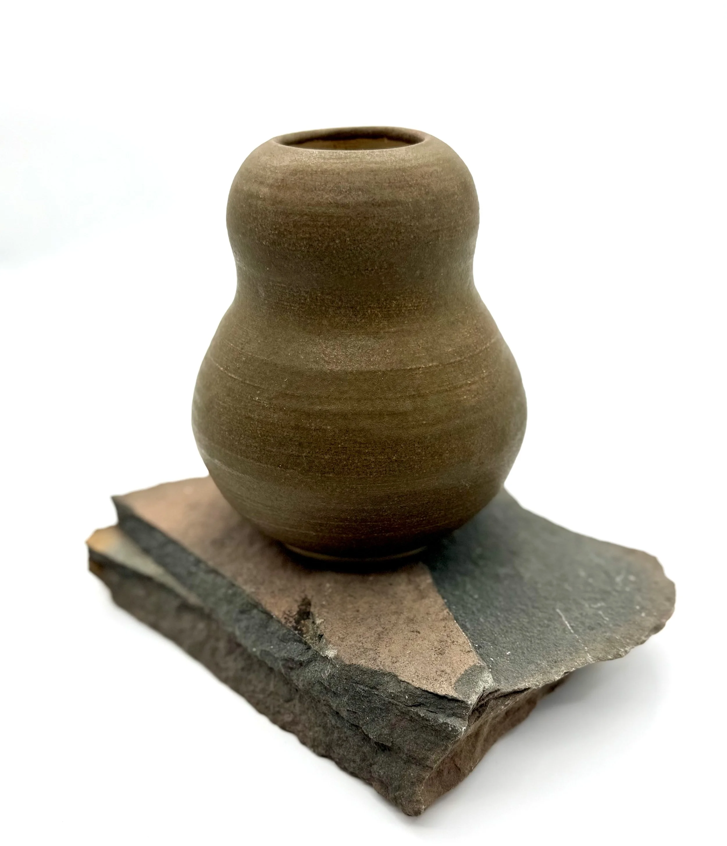 Brown ceramic vase with a smooth, rounded shape, placed on a piece of rough stone.
