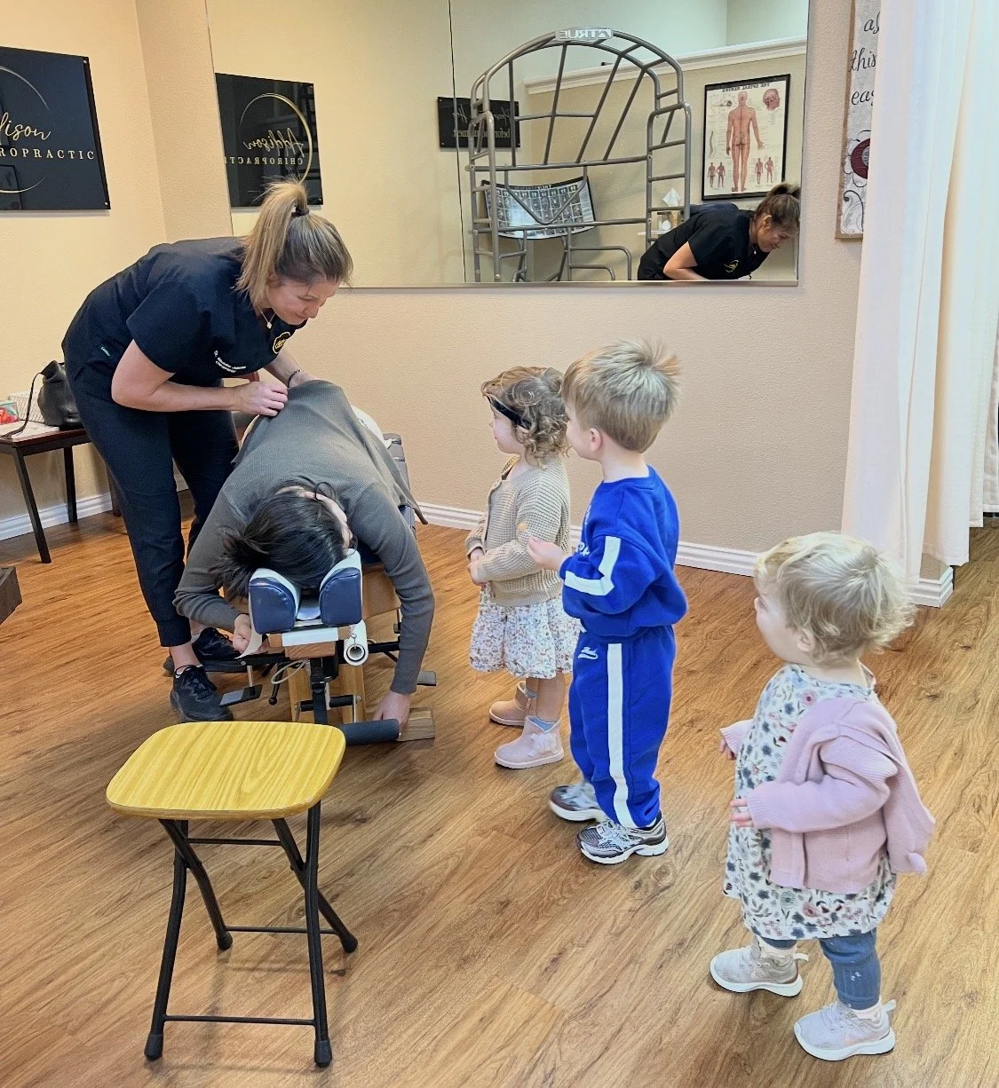 Pregnant woman getting adjustment while children watch