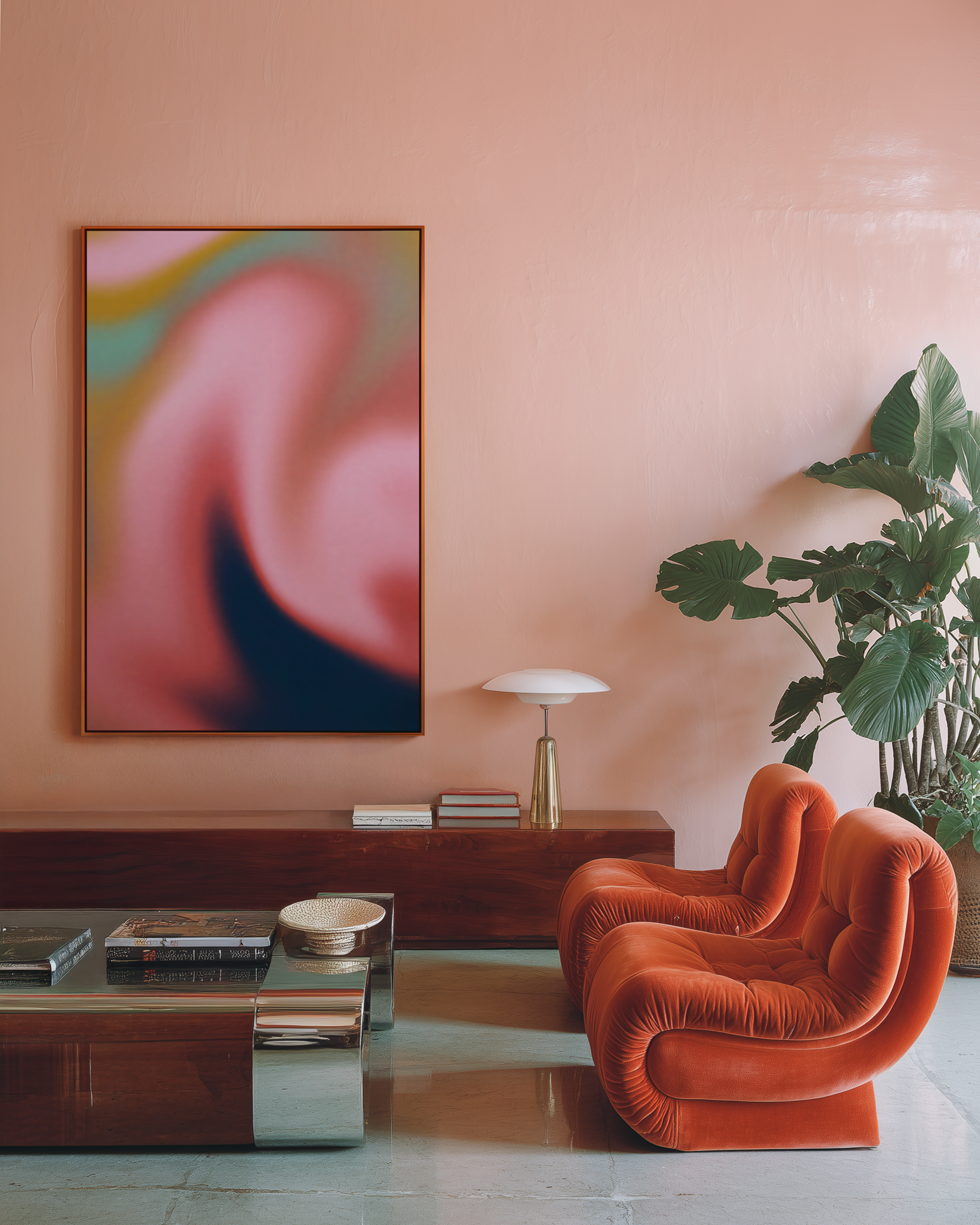 A living room with a pink wall featuring an abstract colorful artwork, a wooden console table with books and decorative items, a table lamp, a green plant, and an orange velvet armchair.