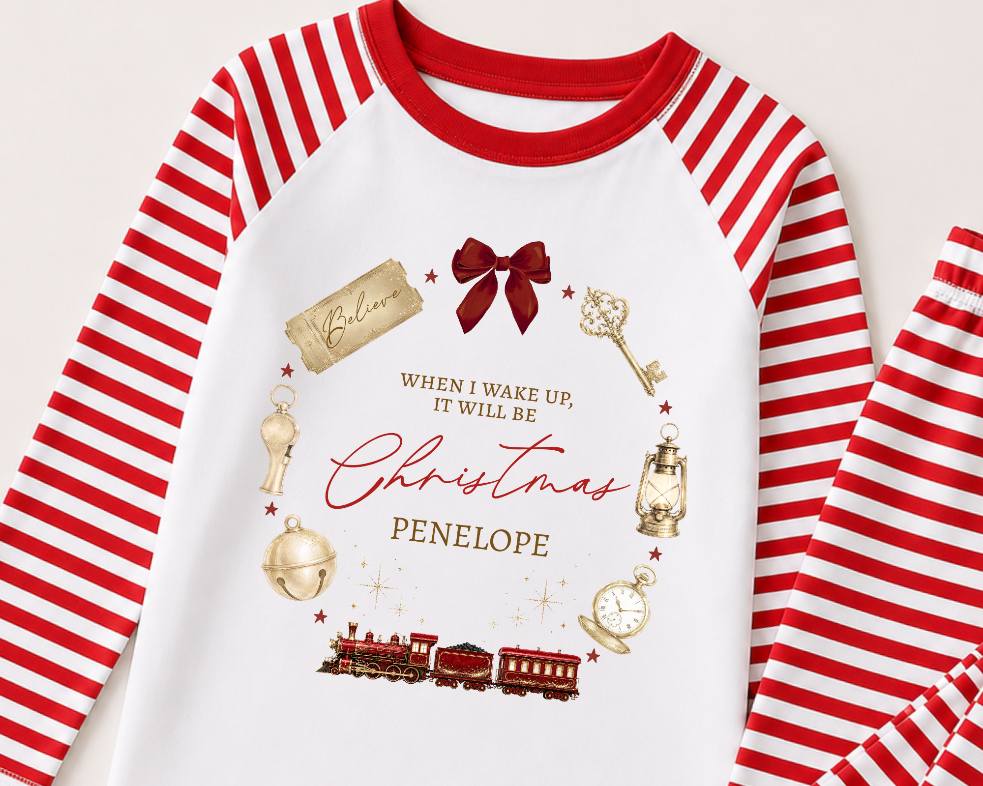 Christmas-themed long sleeve shirt with red and white striped sleeves and red collar, decorated with vintage gold and brass objects, including a train, clock, lantern, and key, along with a red bow and festive text.