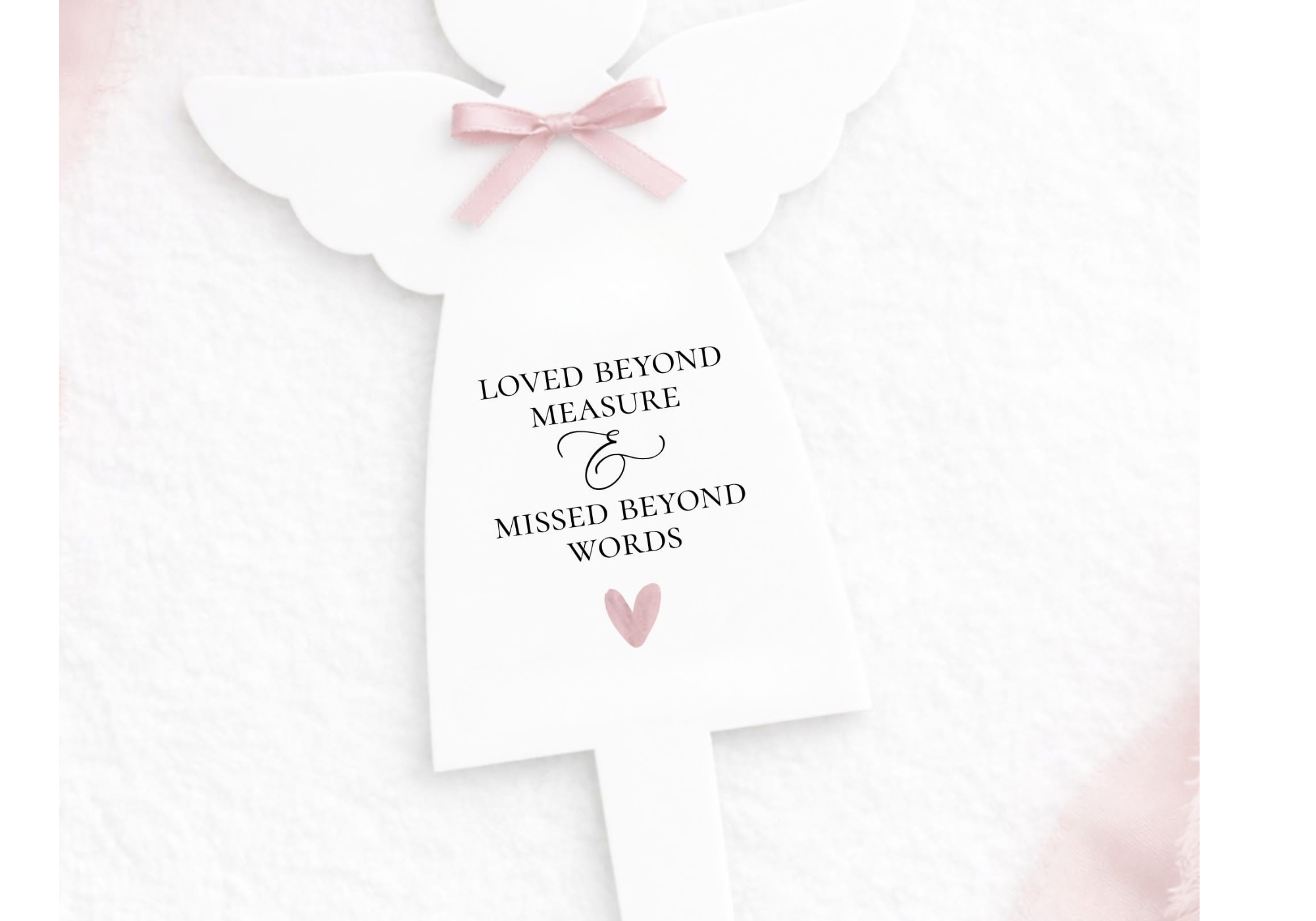 A white card with a pink bow and a pink heart at the bottom. The card has the text, "Loved beyond measure & missed beyond words."