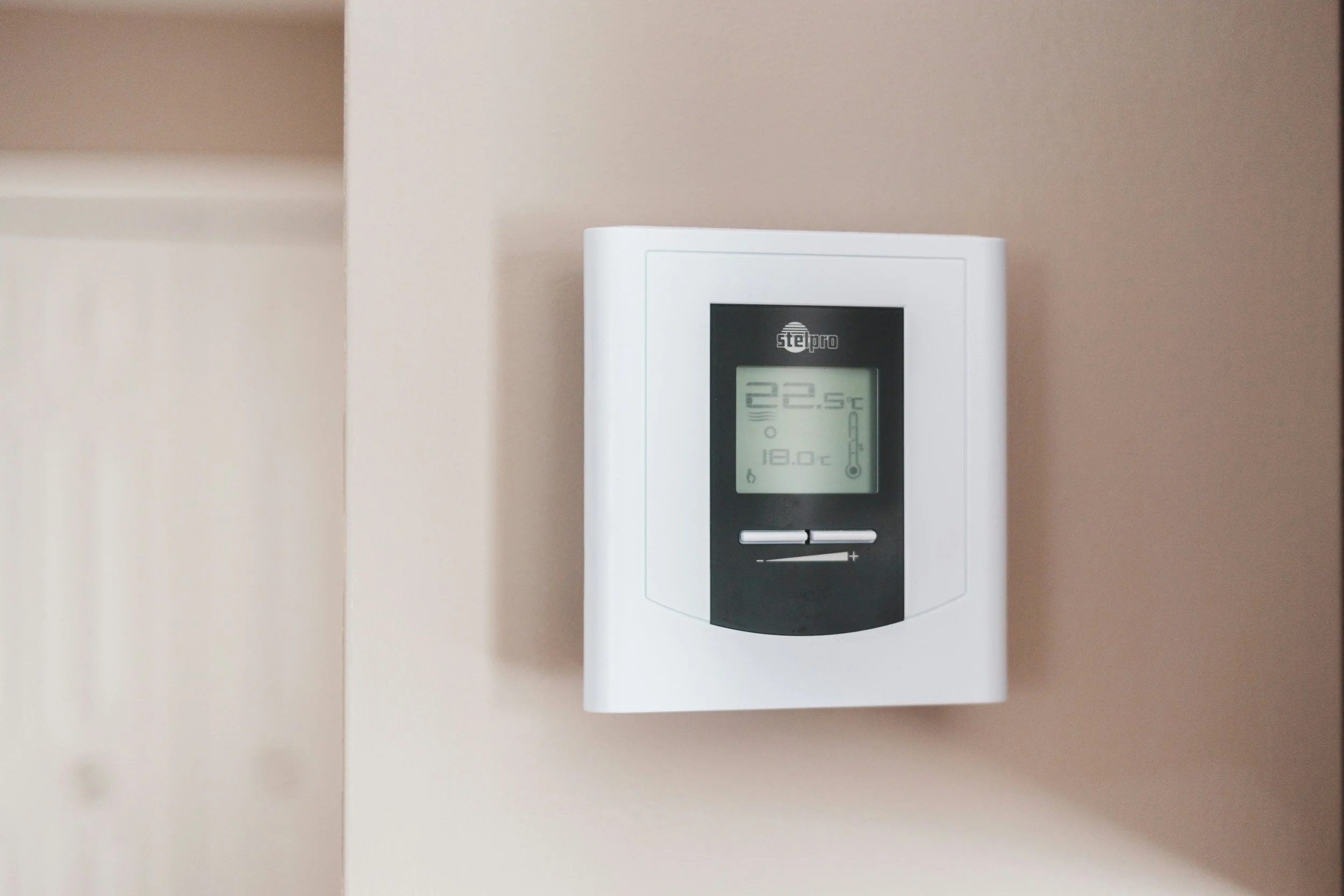 Digital thermostat mounted on a wall, displaying a temperature of 22.5°C.